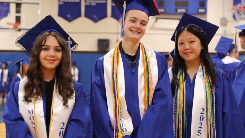 three students in graduation robes are posing