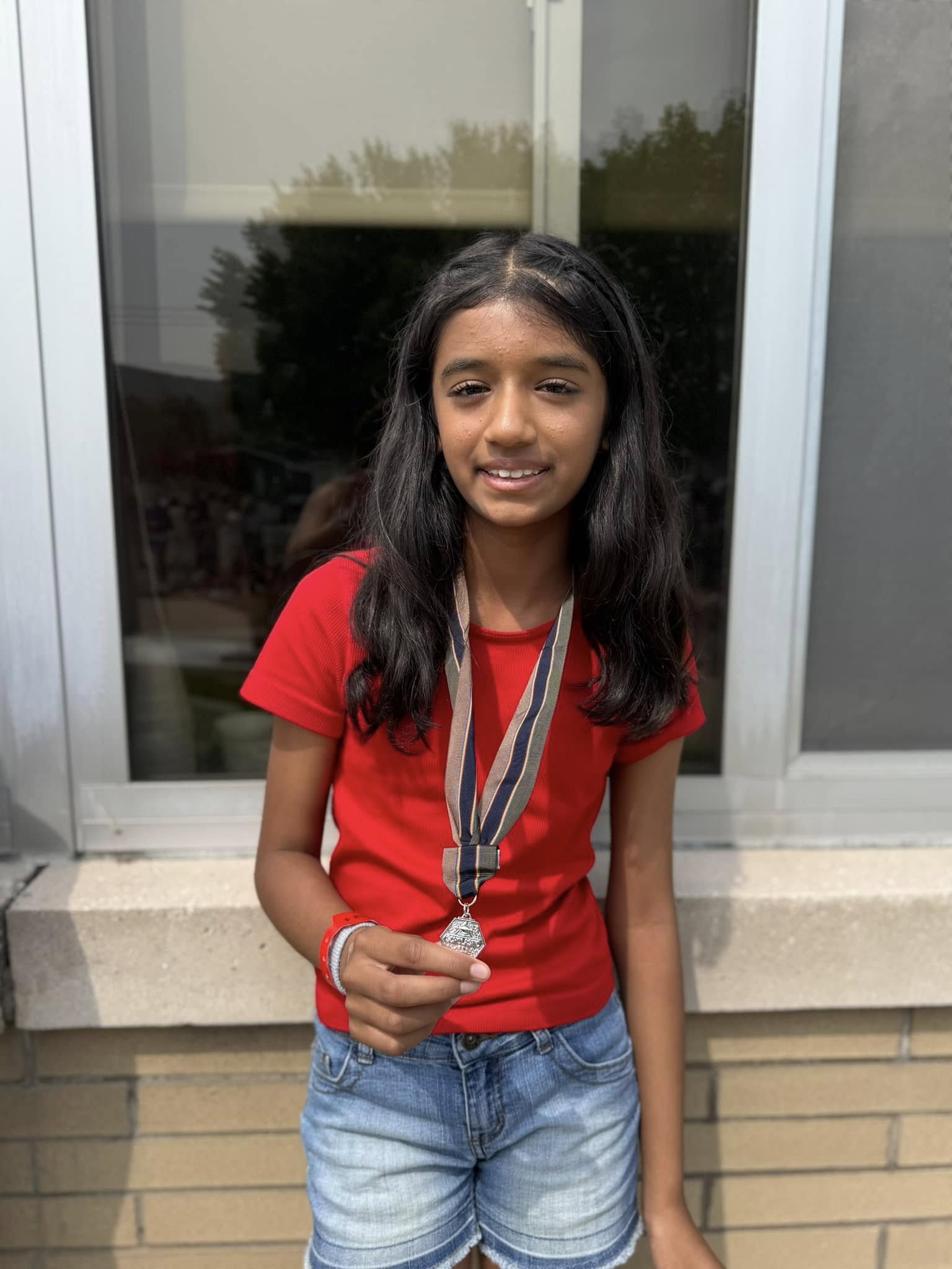 a student smiles, holding up a silver medal