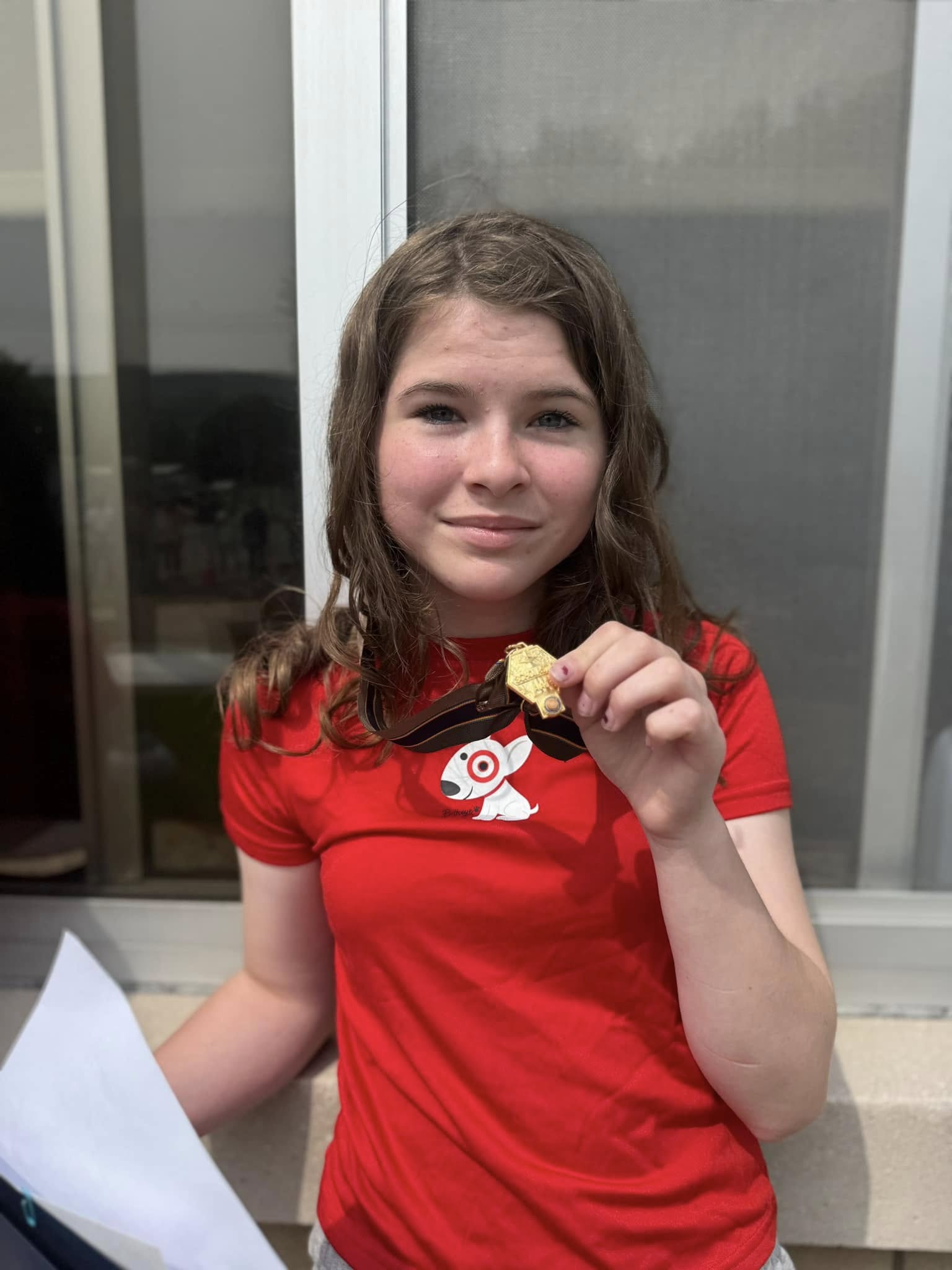 a student smiles holding up a gold medal