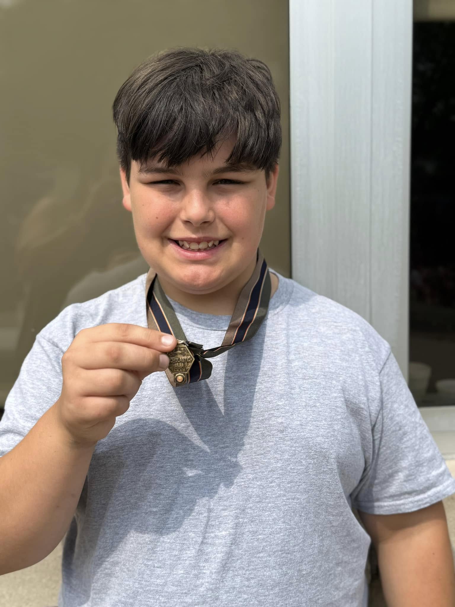 a student smiles holding up a bronze medal