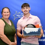 students are posing in front of a backdrop holding their awards