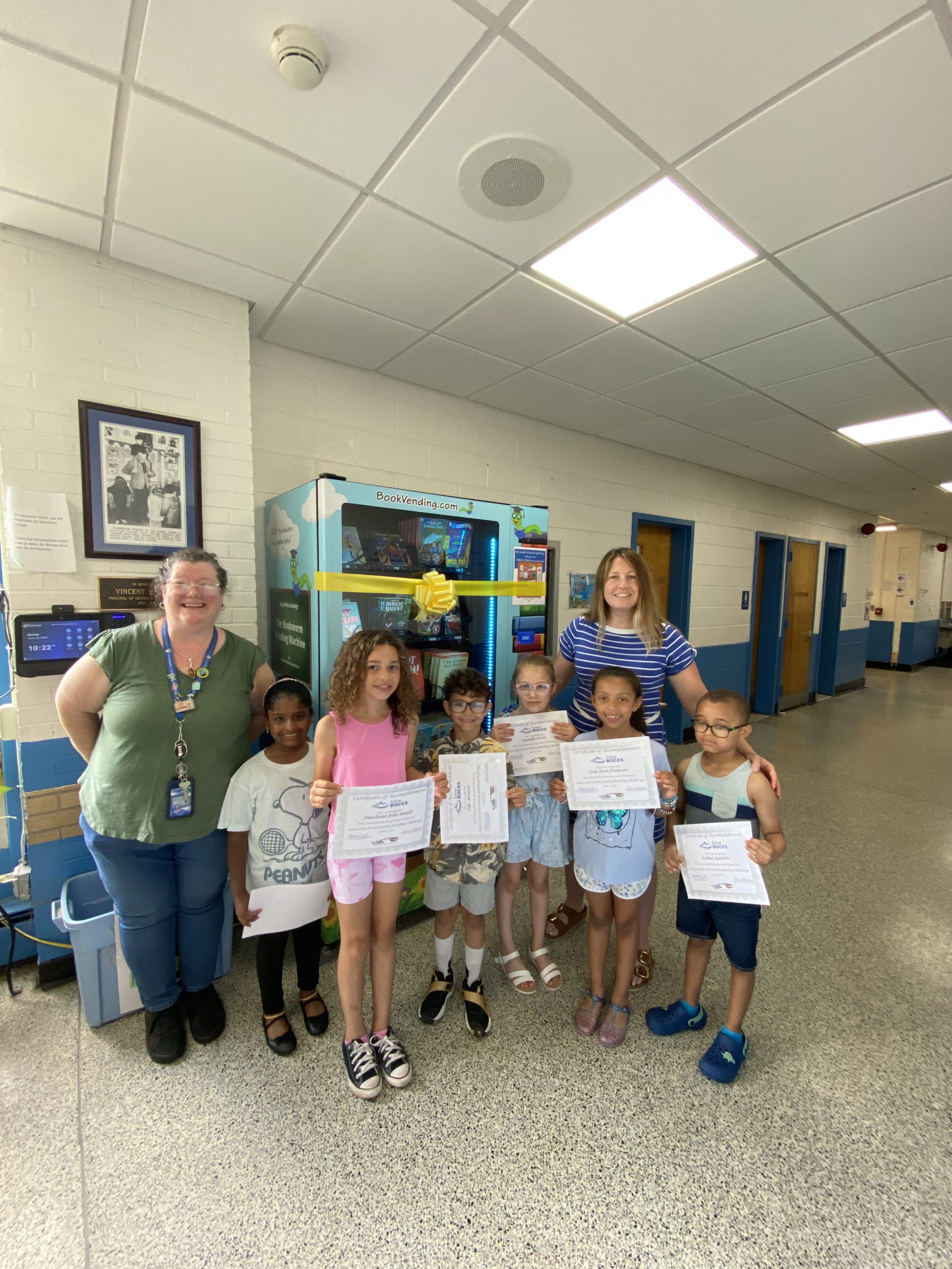 students holding books are smiling in front of a vending machine