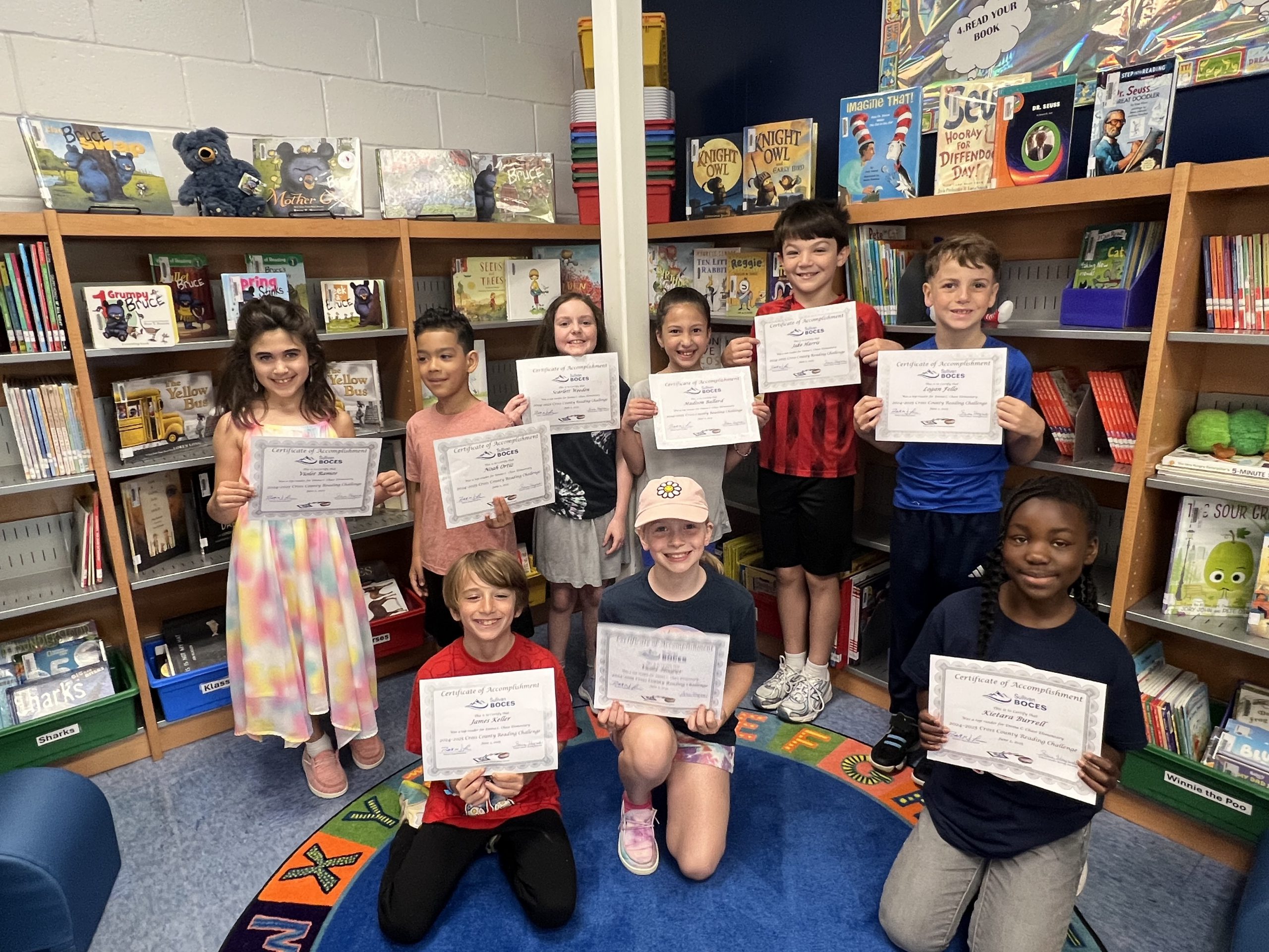 a group of students are posing in the library, and holding up certificates