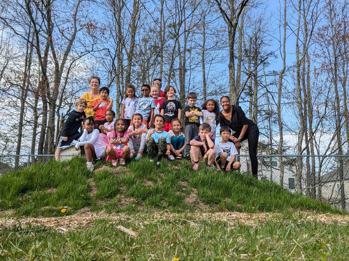 members of the Spartan Club and their advisors are seated on a hill, smiling 