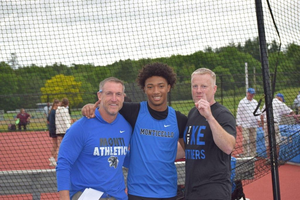 Quenten Liciaga poses on the track, flanked by his coaches 