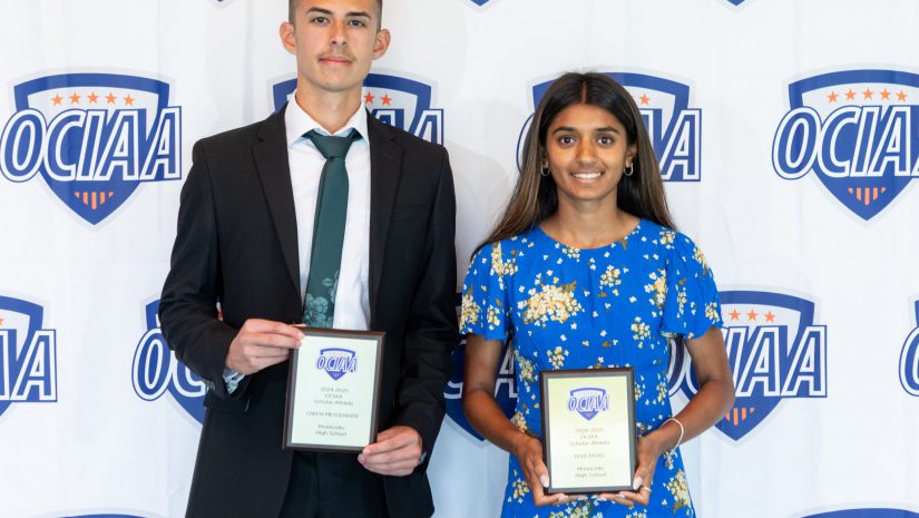 Diya and Owen are posing in front of a backdrop holding their awards