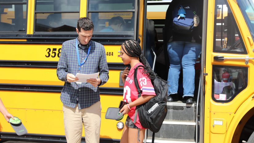 a staff member helps a student find a bus