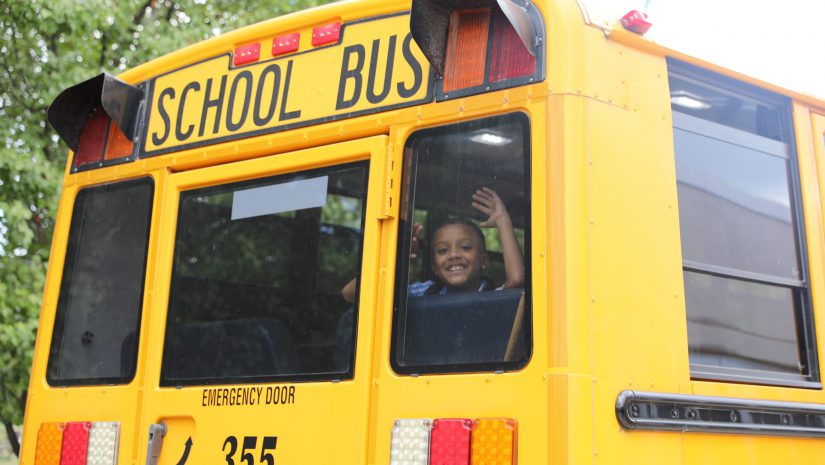 a student is waving out the window of a bus
