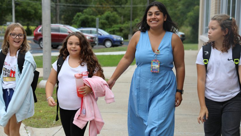 three students and a teacher are walking