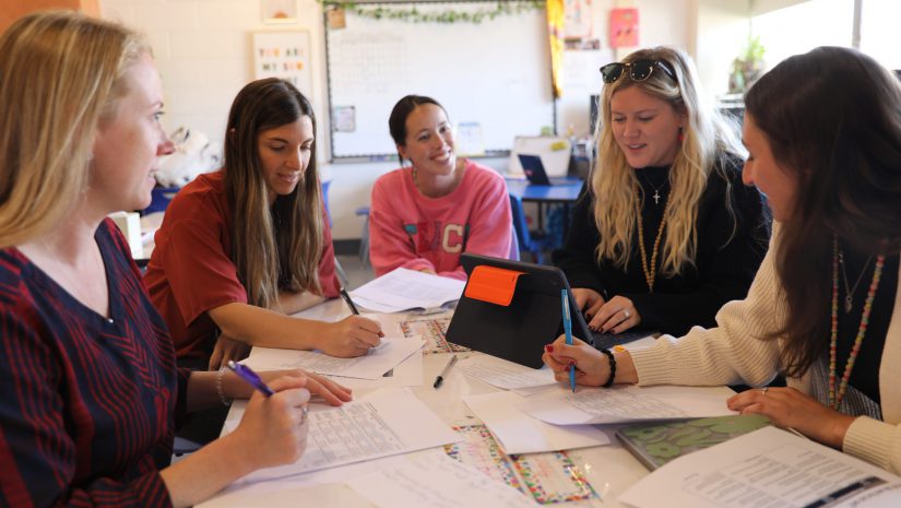a group of teachers are engaged in a discussion around the table