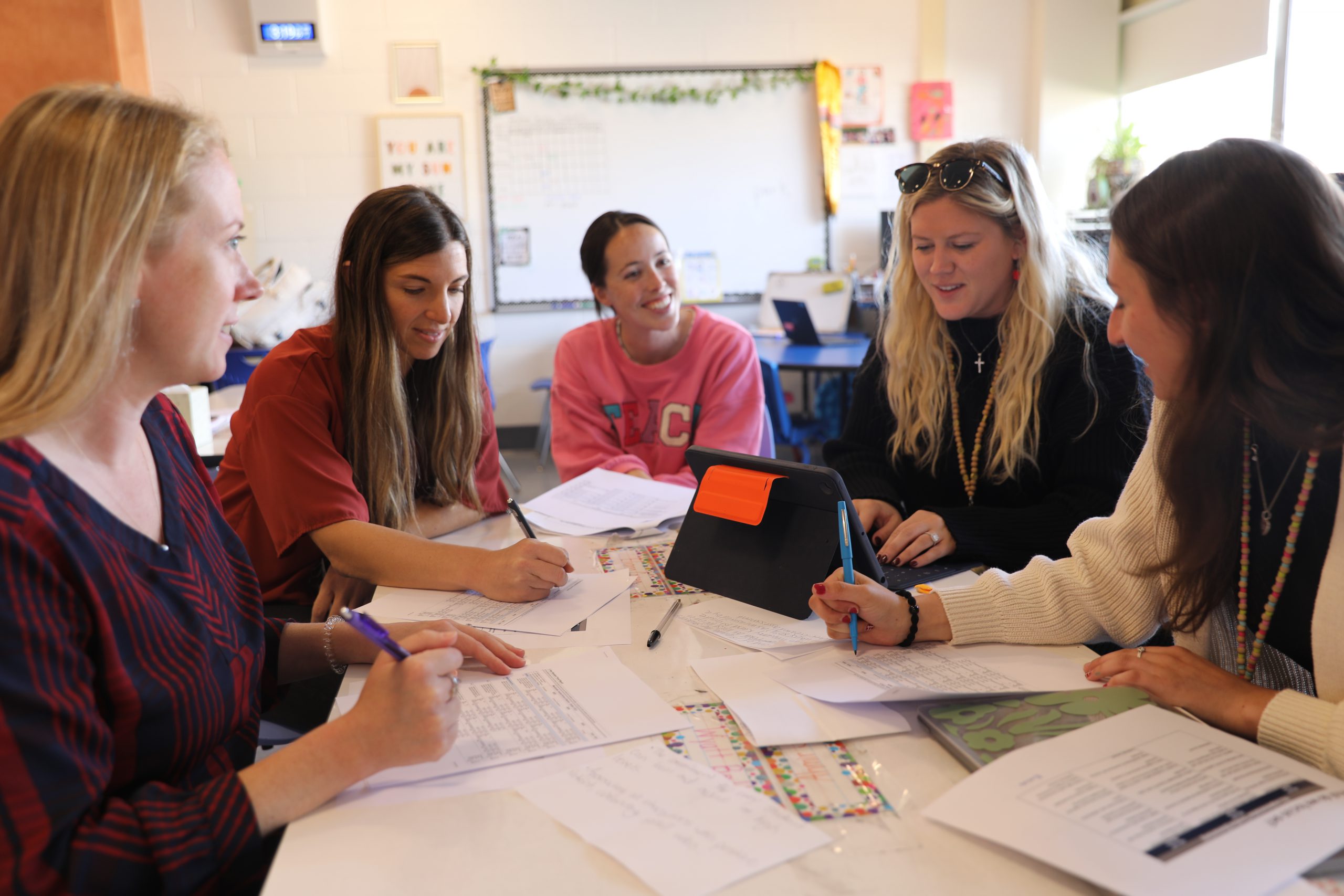 a group of teachers are engaged in a discussion around the table