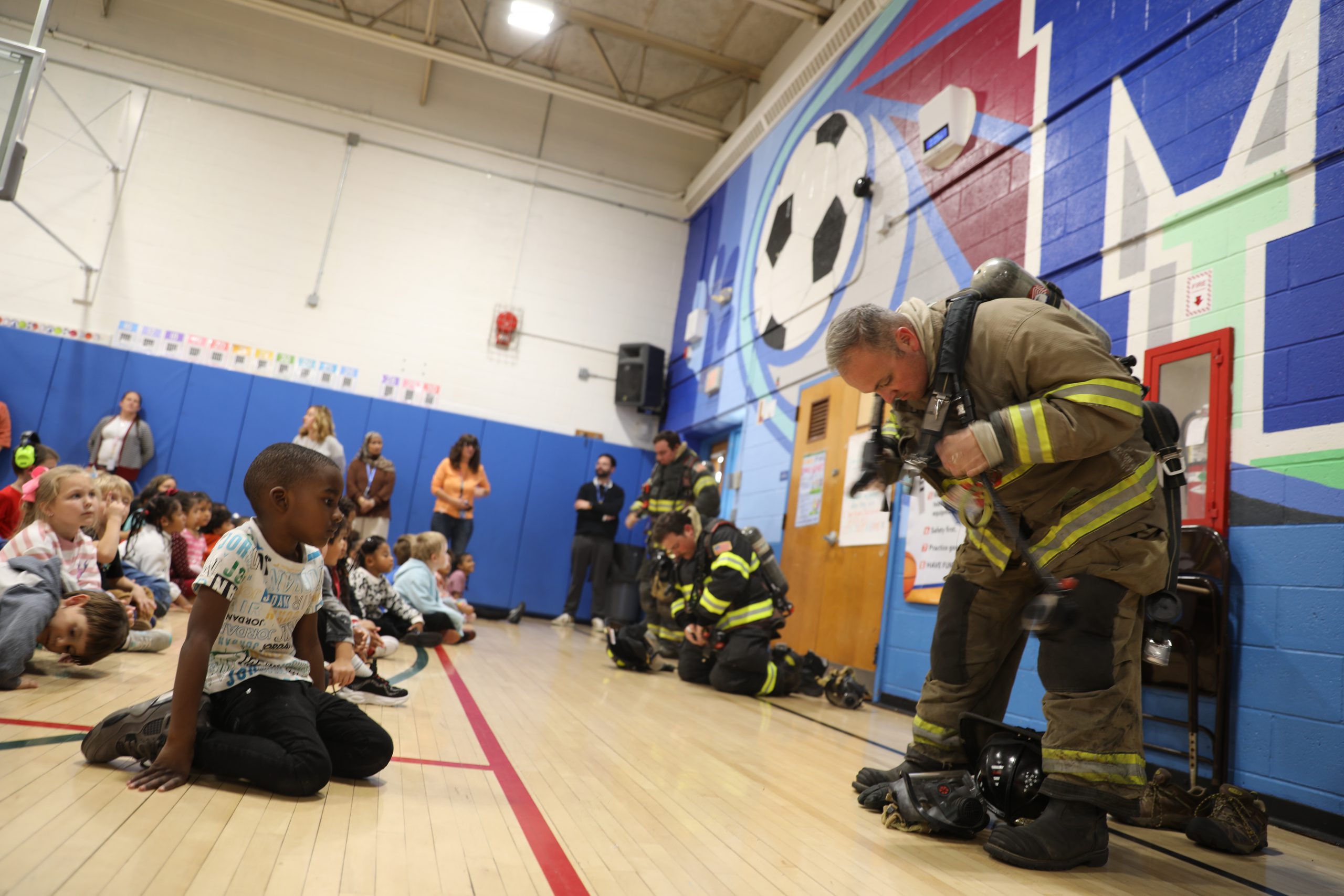 students watch a fireman put on gear