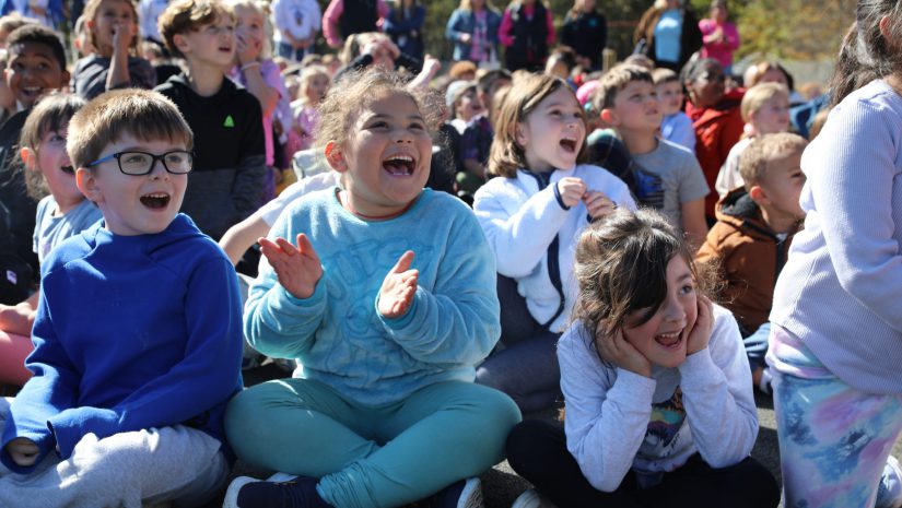 three students react happily to the fire equipment demonstration
