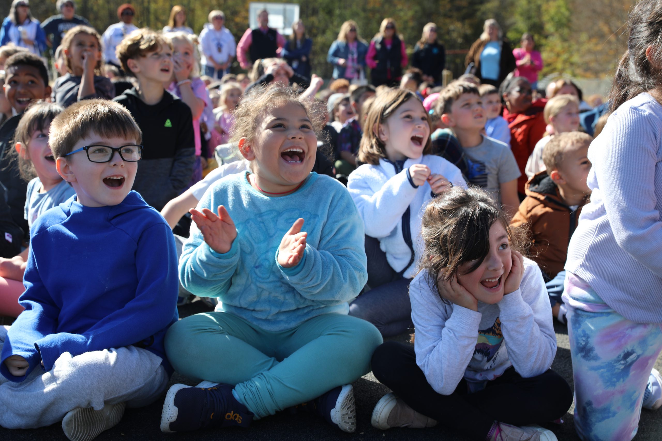 three students react happily to the fire equipment demonstration