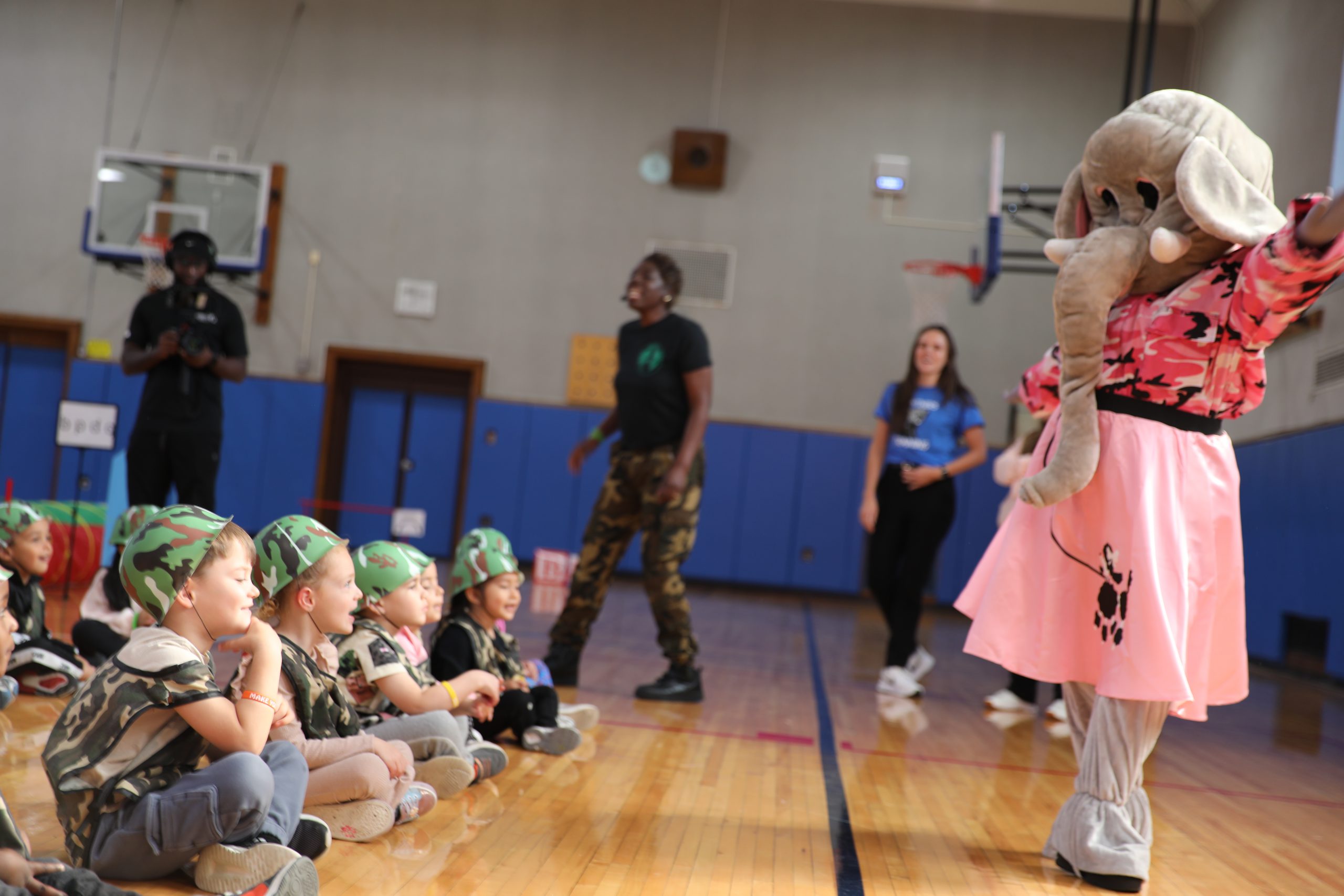 students are seated and looking up at a mascot