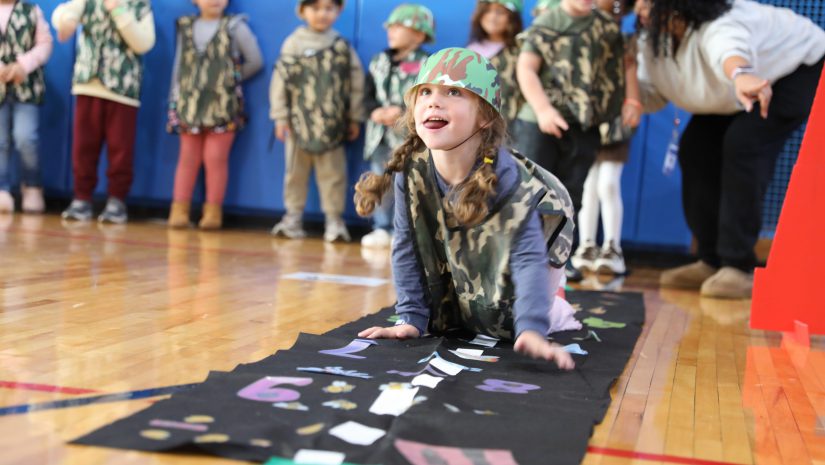 a student crawls through an obstacle course