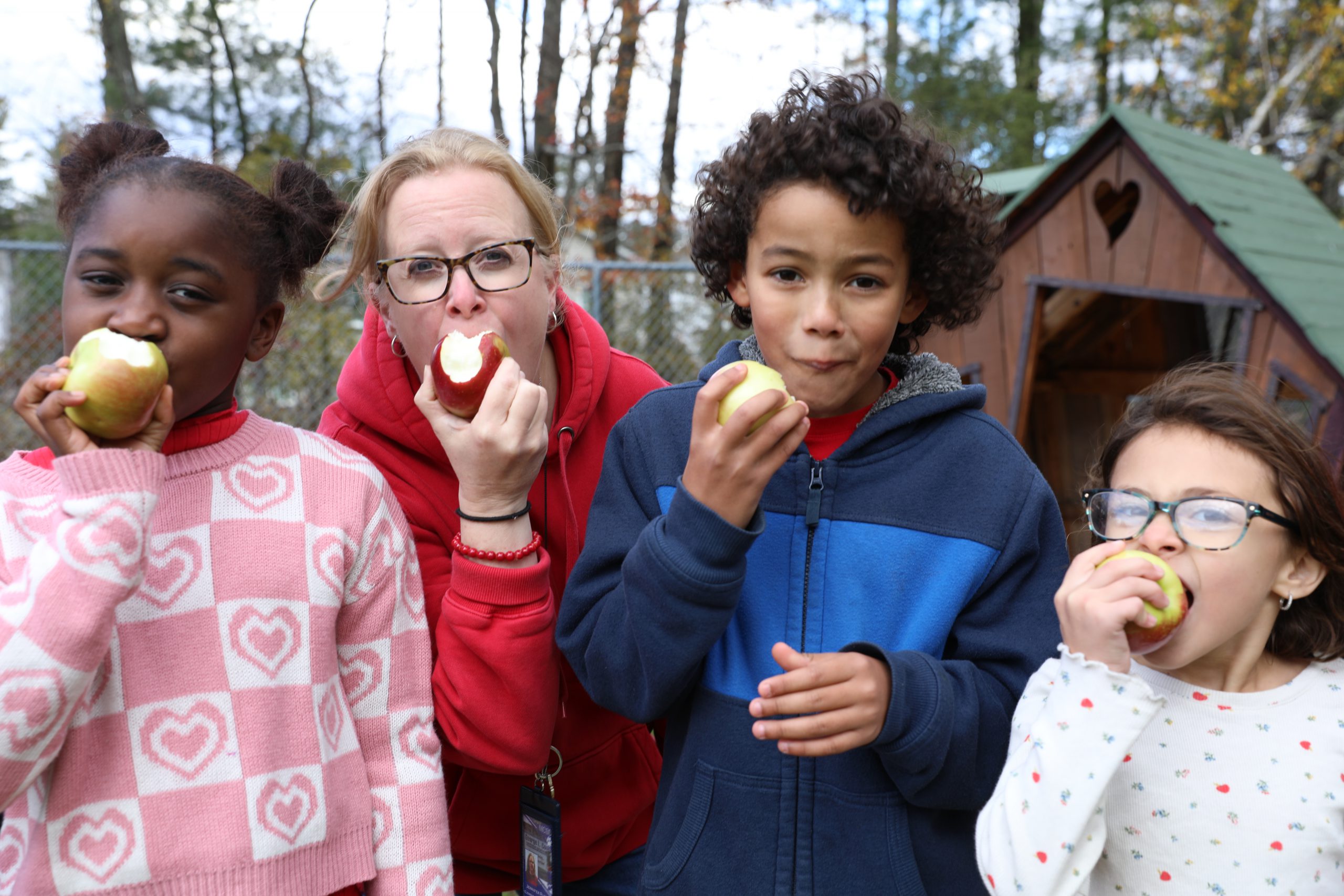 3 students and a teacher are crunching into an apple