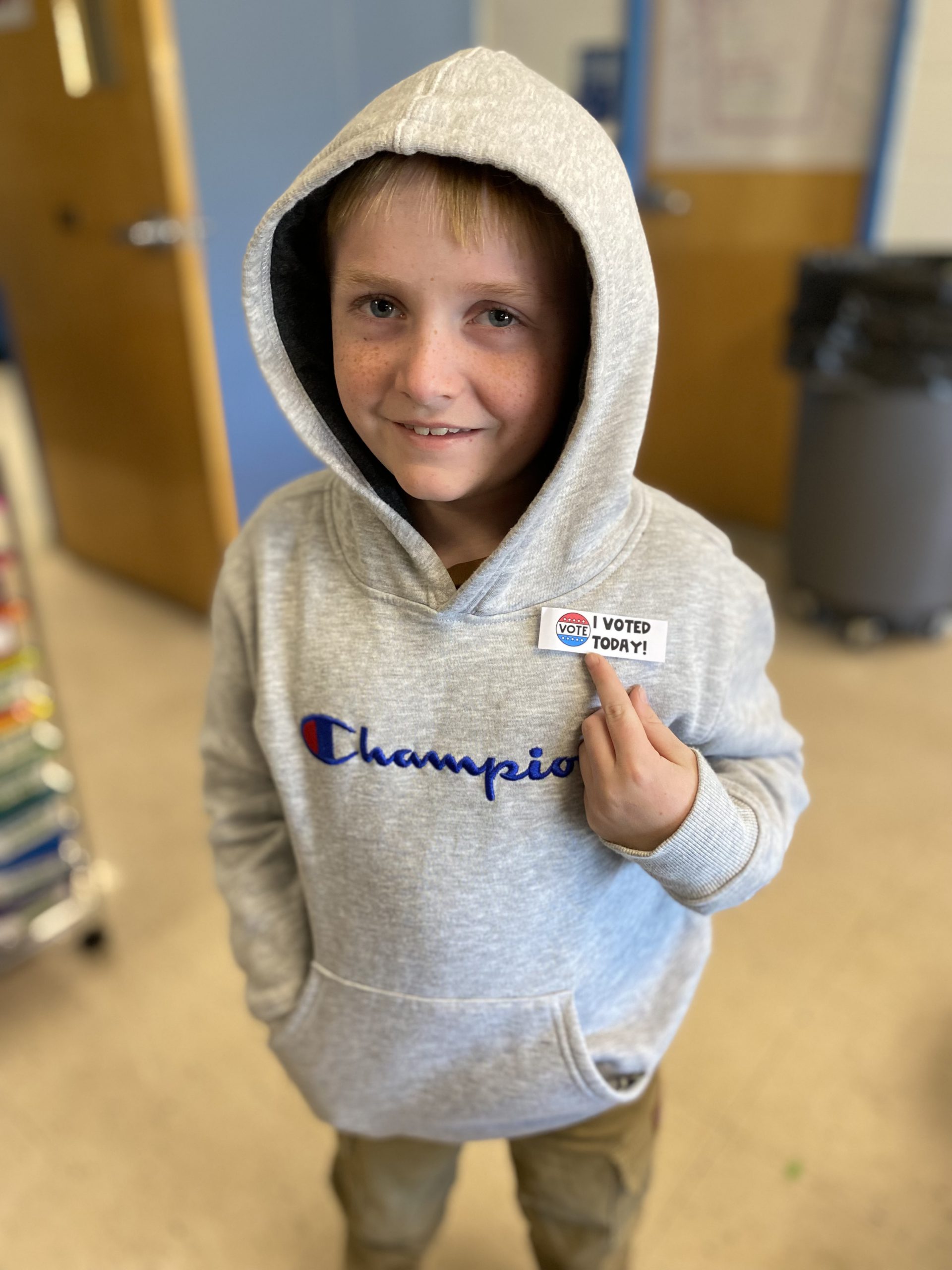 a student points to an "I voted" sticker