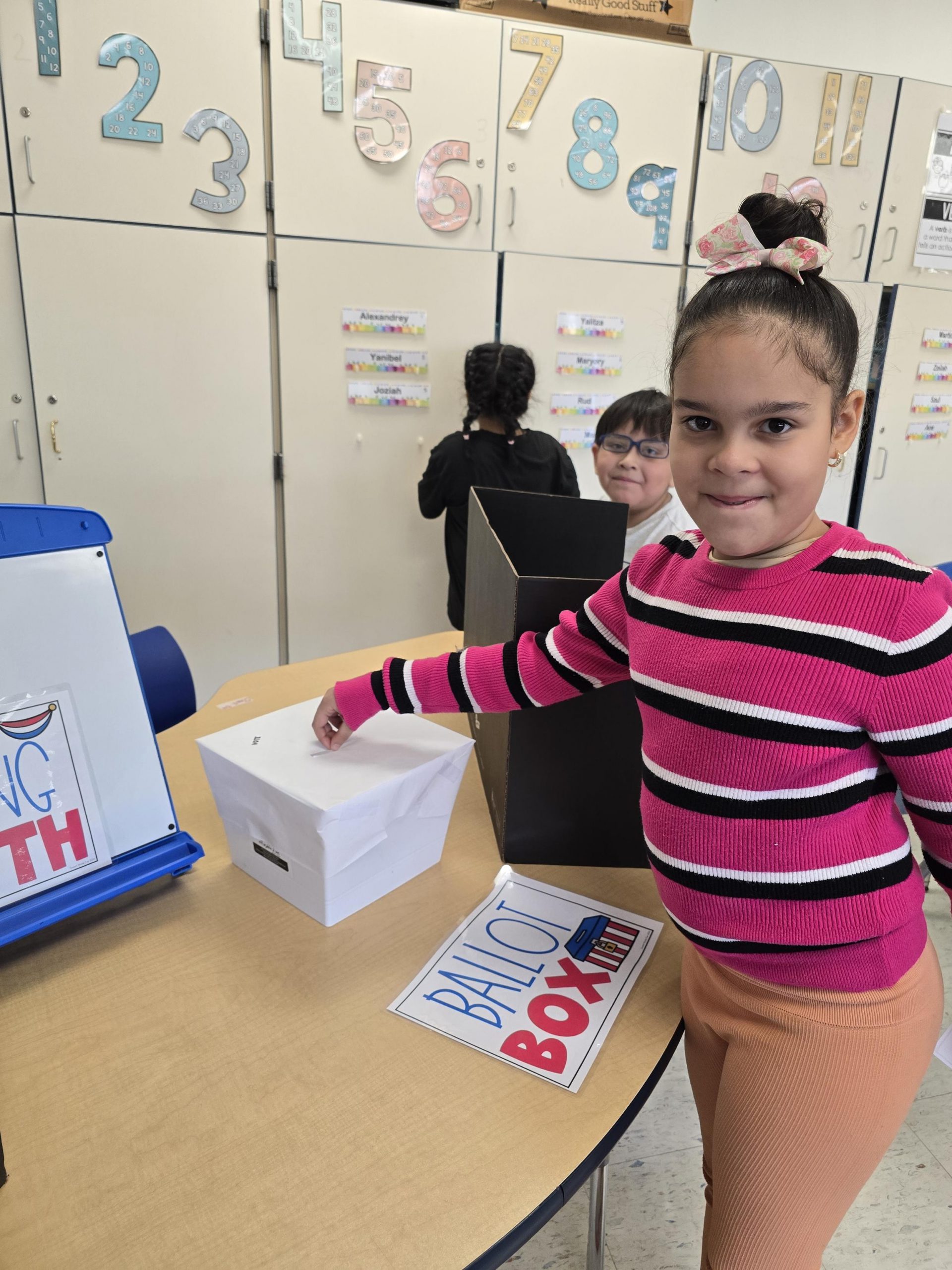 a young girl is putting a ballot into a ballot box.