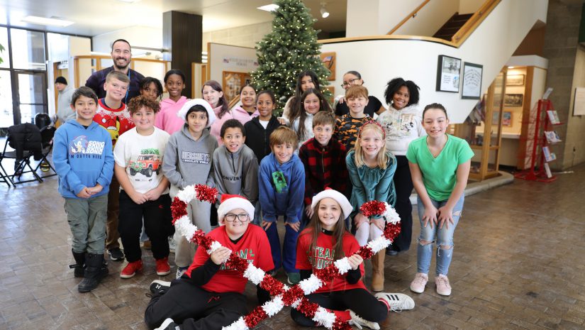 a group of students posing in front of a Christmas tree during a performance