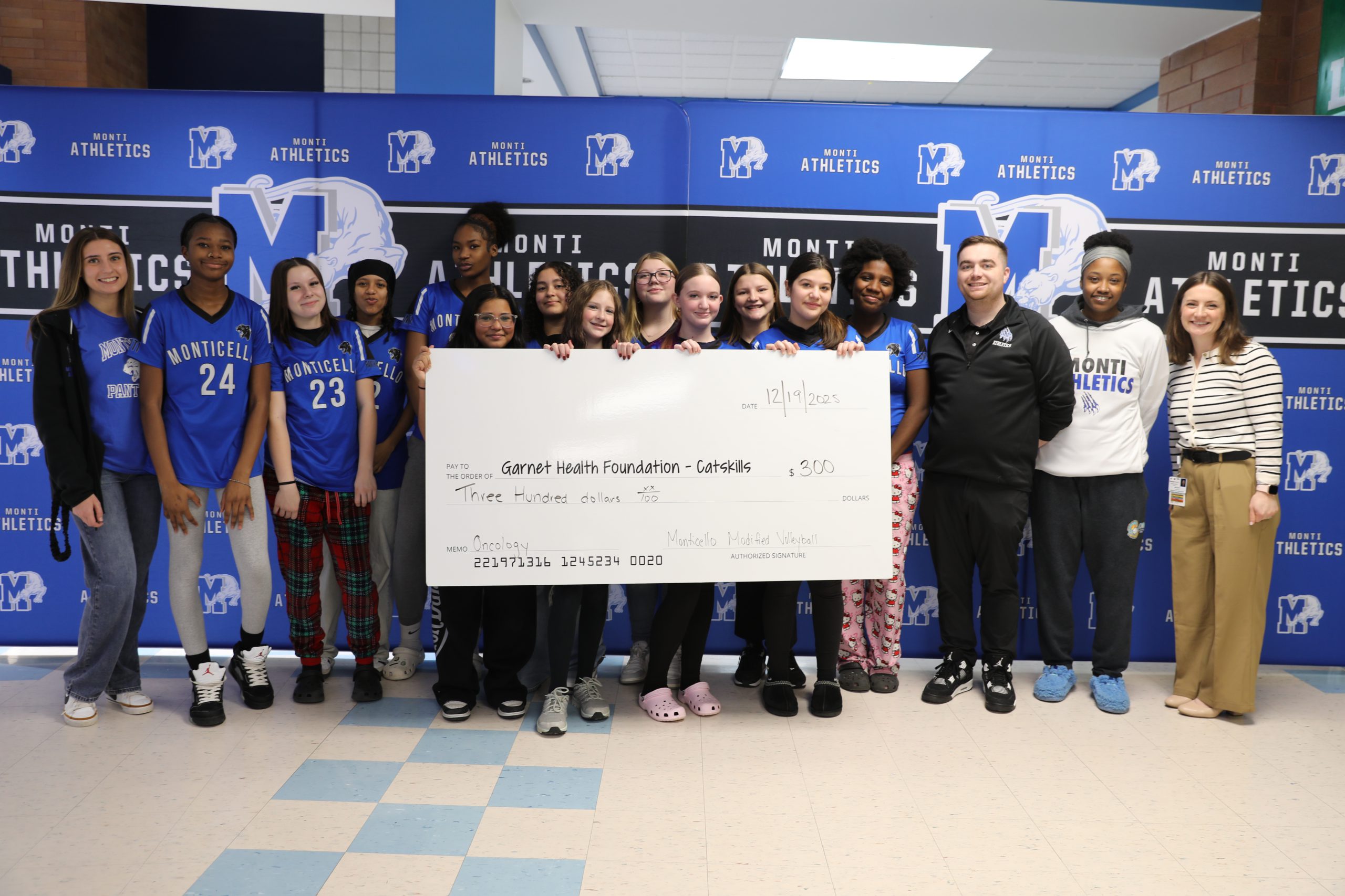 the girls modified volleyball team is posing with their coaches and holding a ceremonial check 
