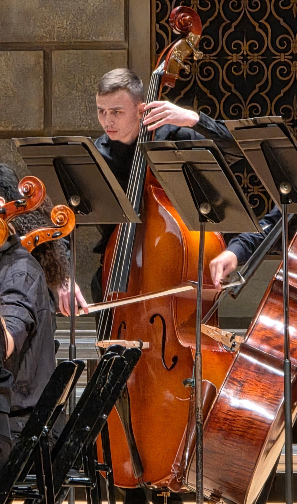 Kenny is playing a cello on stage