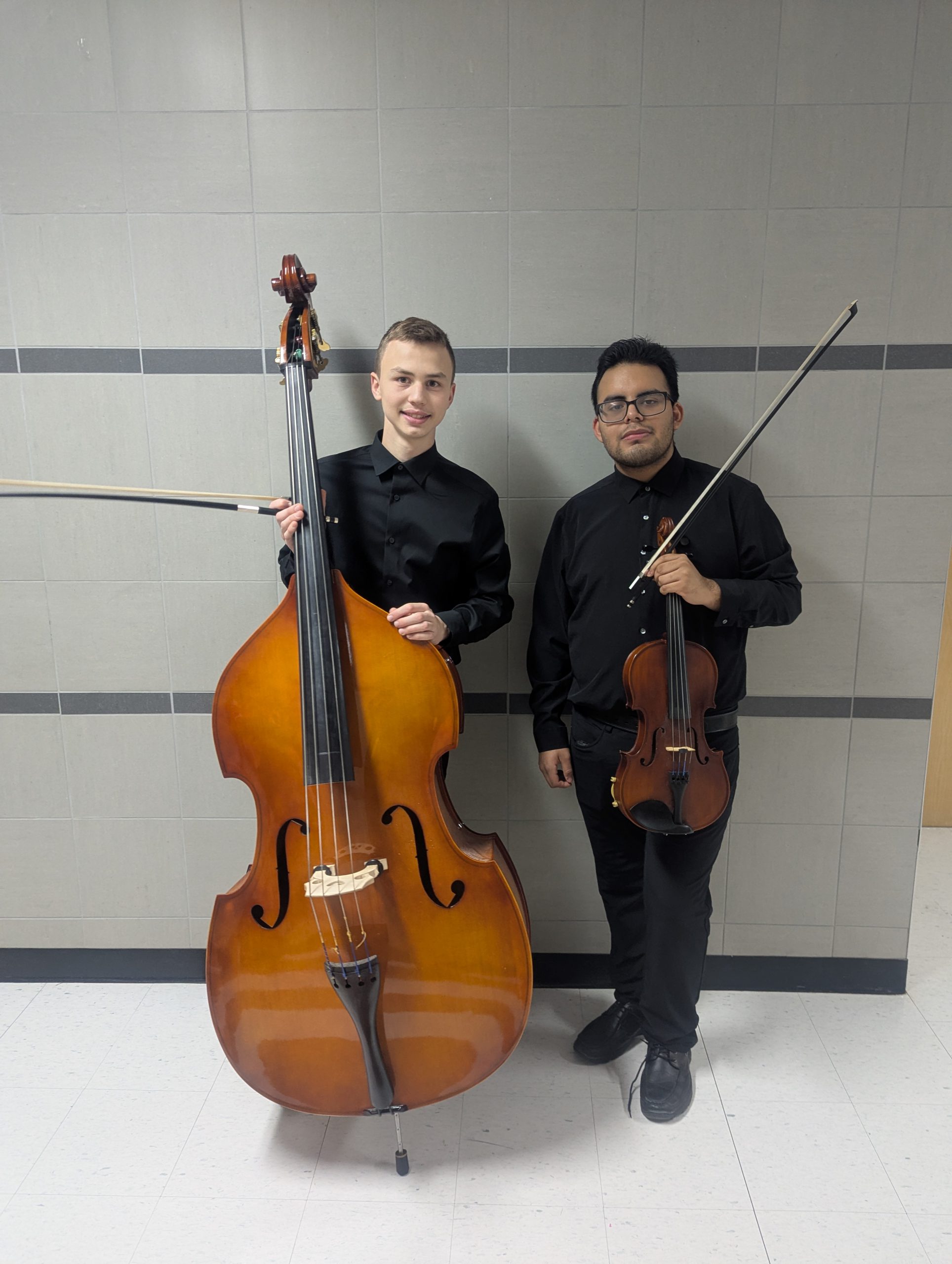 two student musicians pose with their instruments