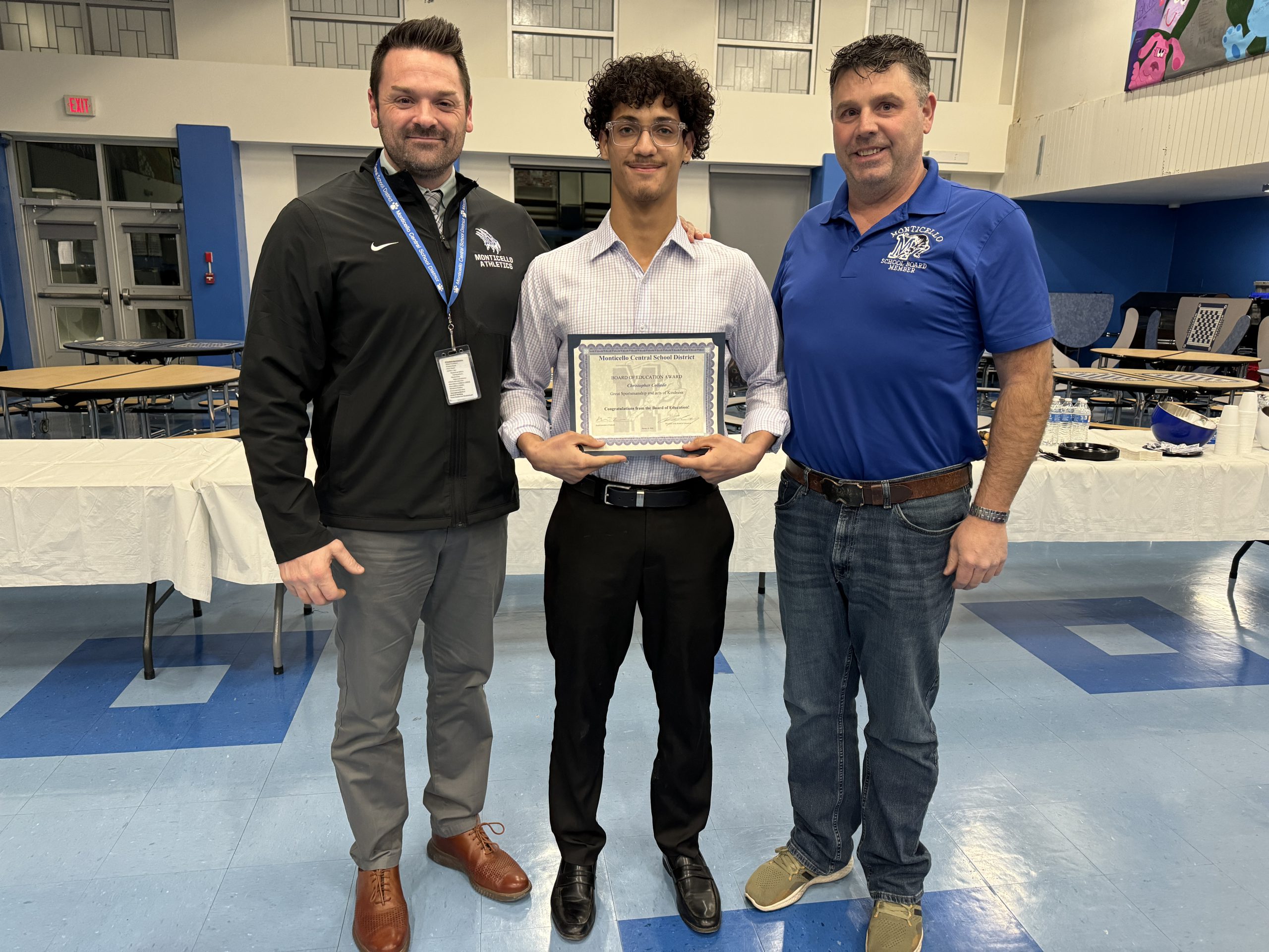 Christopher Collado is holding up his award, and is flanked by Board of Education president Tim Crumley and MCSD Director of Athletics Ryan Jasper