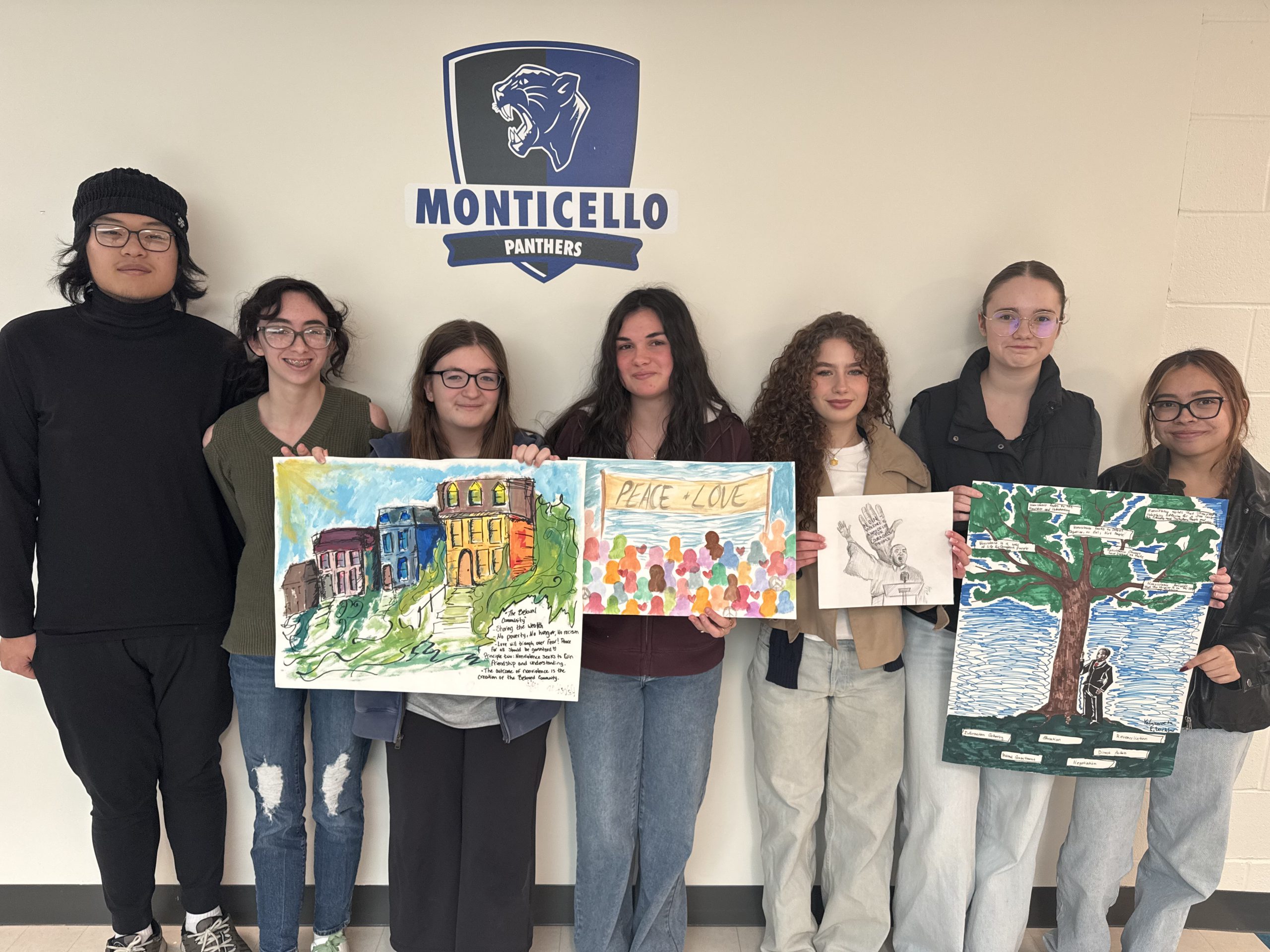 students pose holding their artwork 
