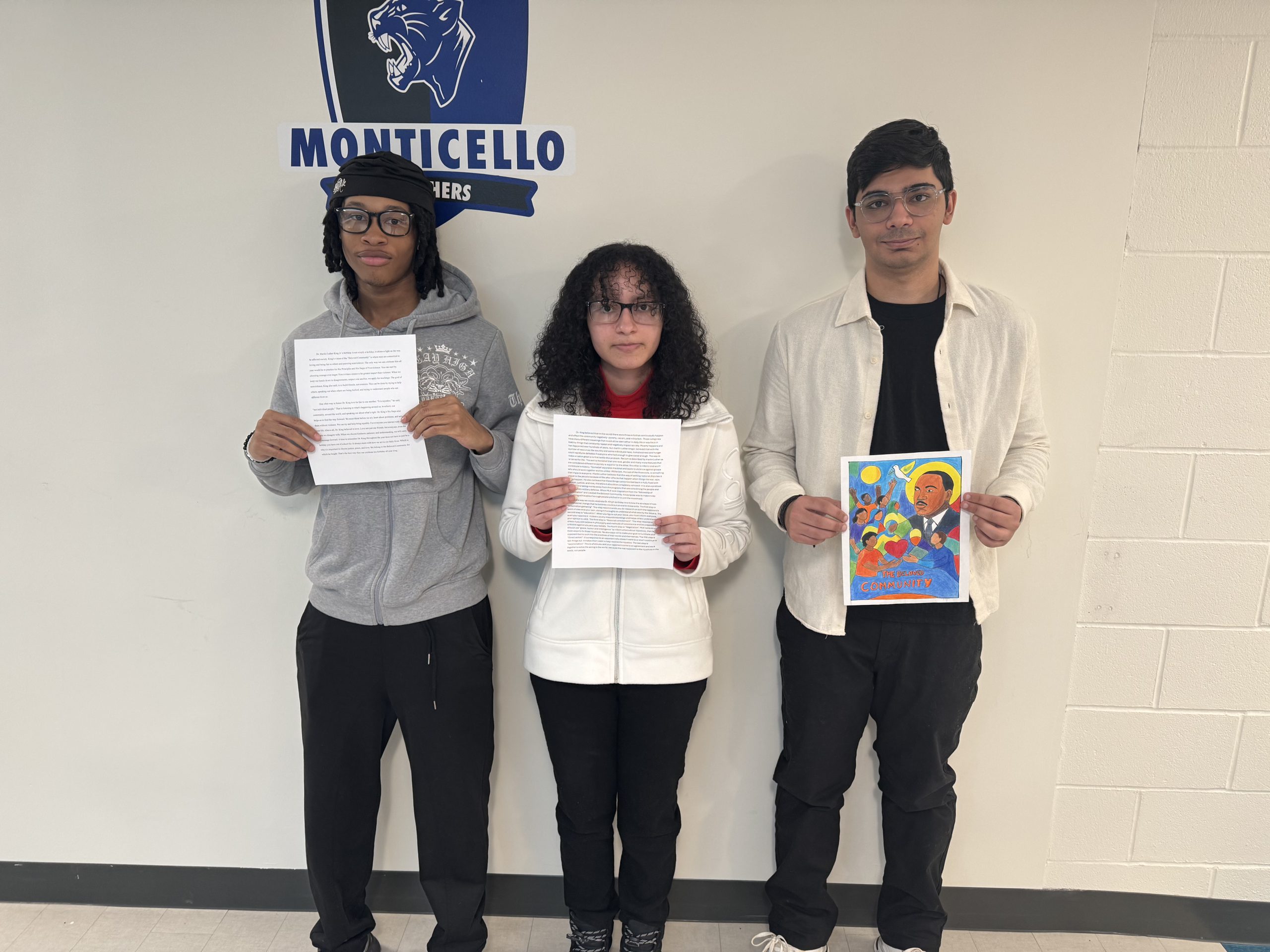 students pose holding up their art work