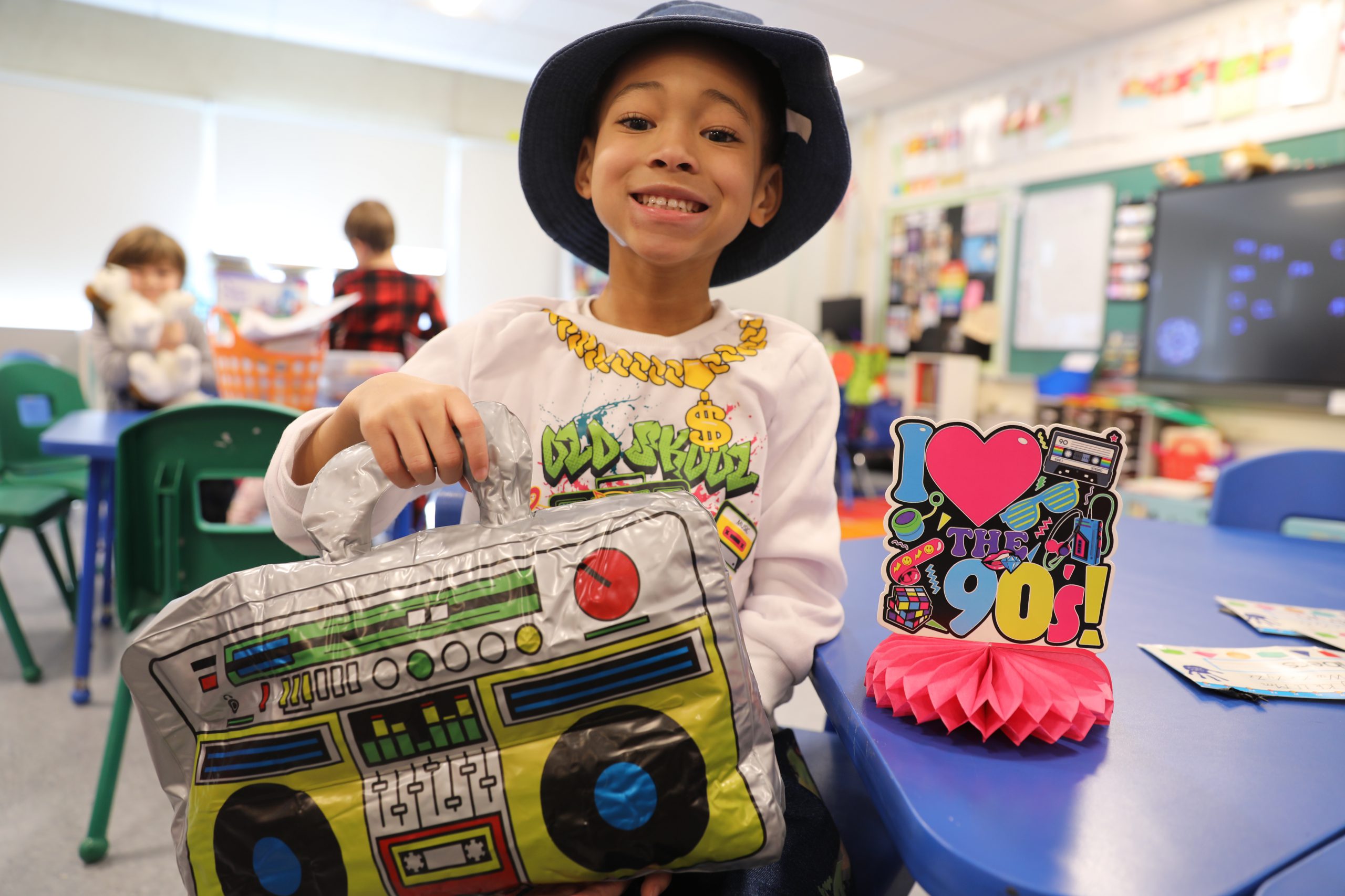 a student wearing a bucket hat and holding an inflatable boom box