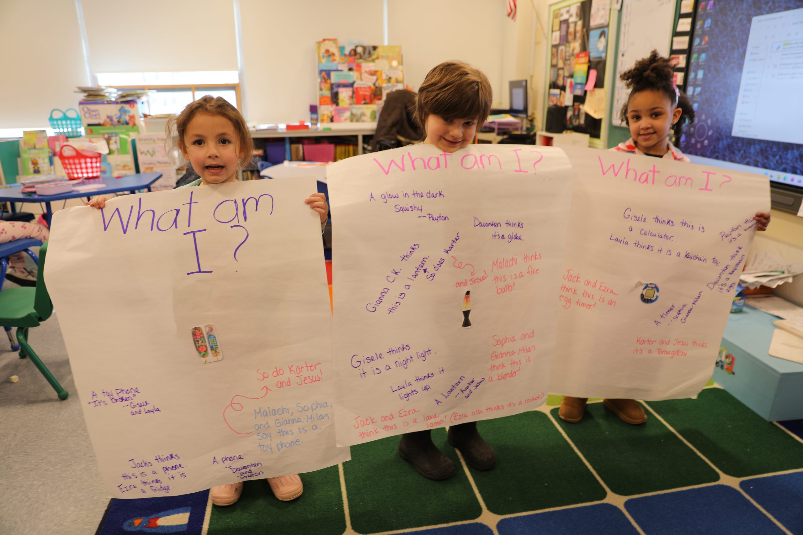 3 students are holding up posters displaying items from the 1990s