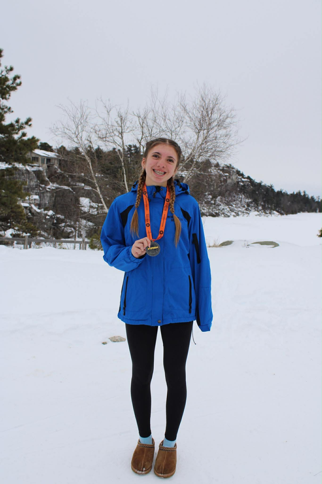 Baya is posing in front of a mountain in the snow and wearing a medal 