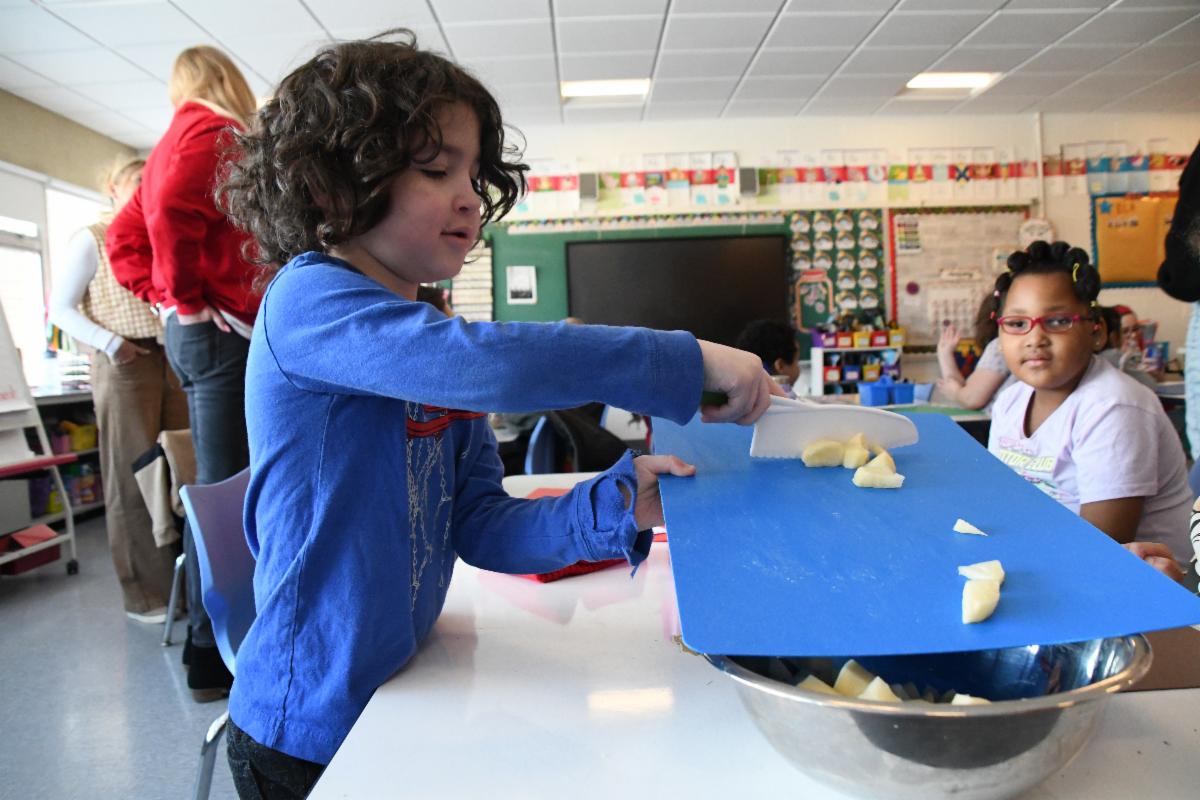 a student is transferring chopped vegetables into a bowl
