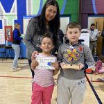 two students hold up a trophy with a teacher