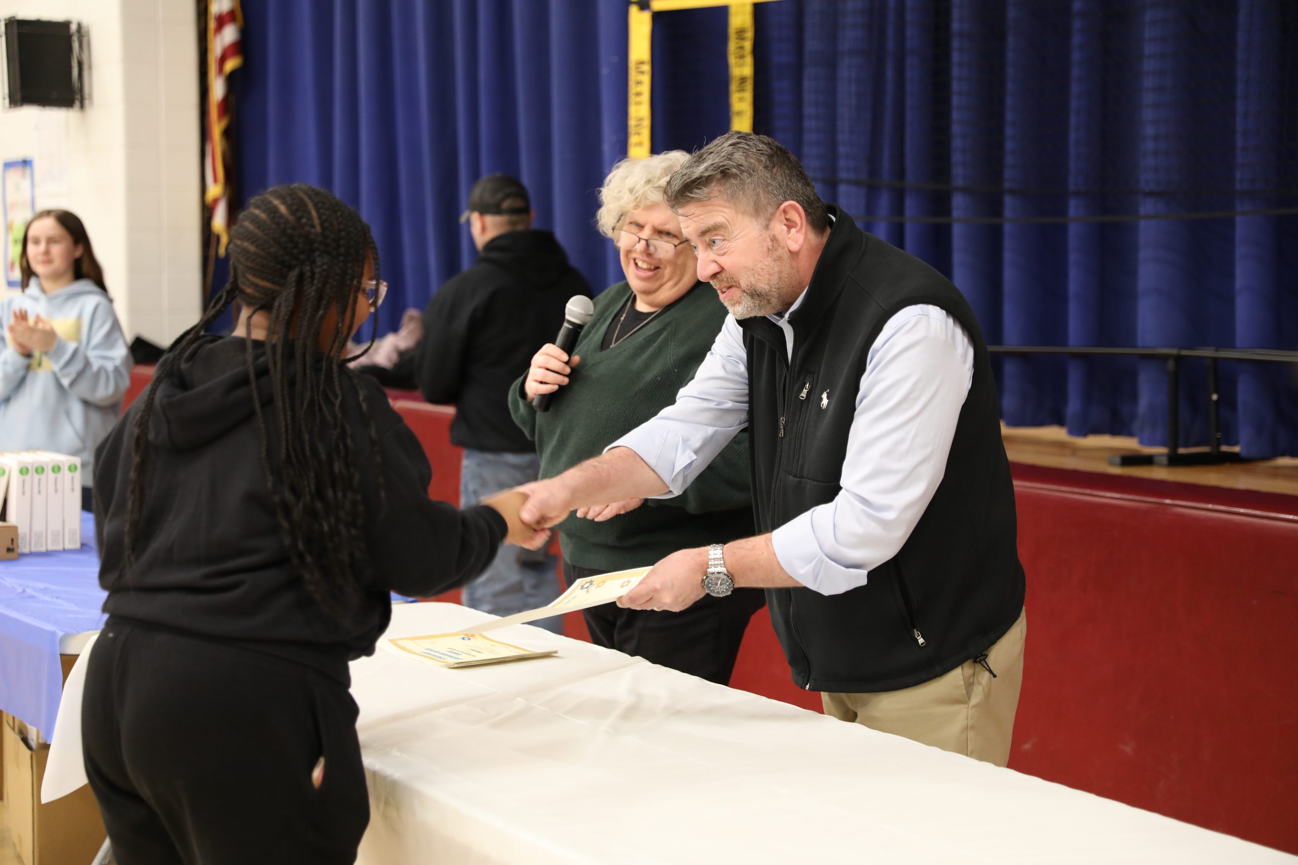 a student receives a certificate from the principal and librarian