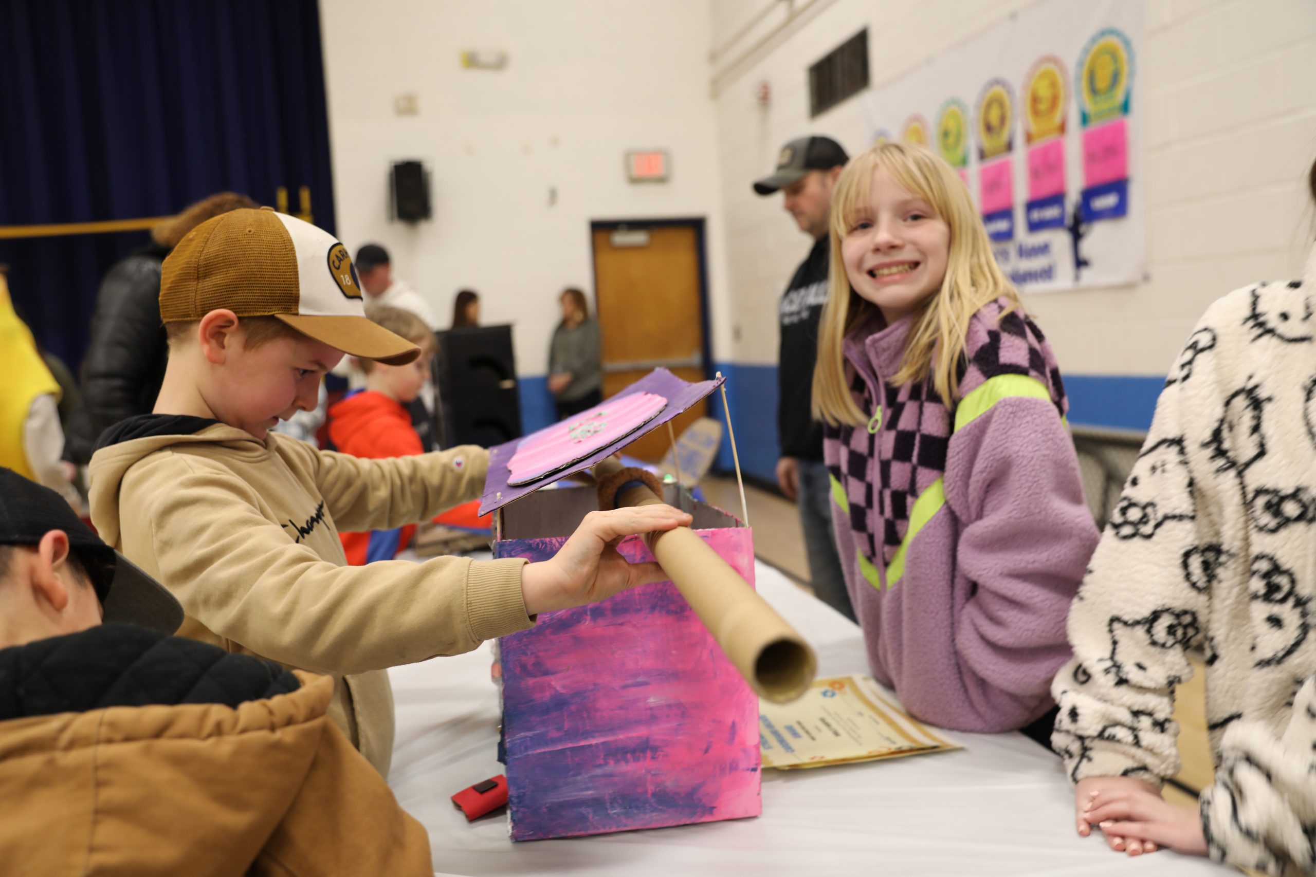 a student plays a game, as another student looks up at the camera smiling 
