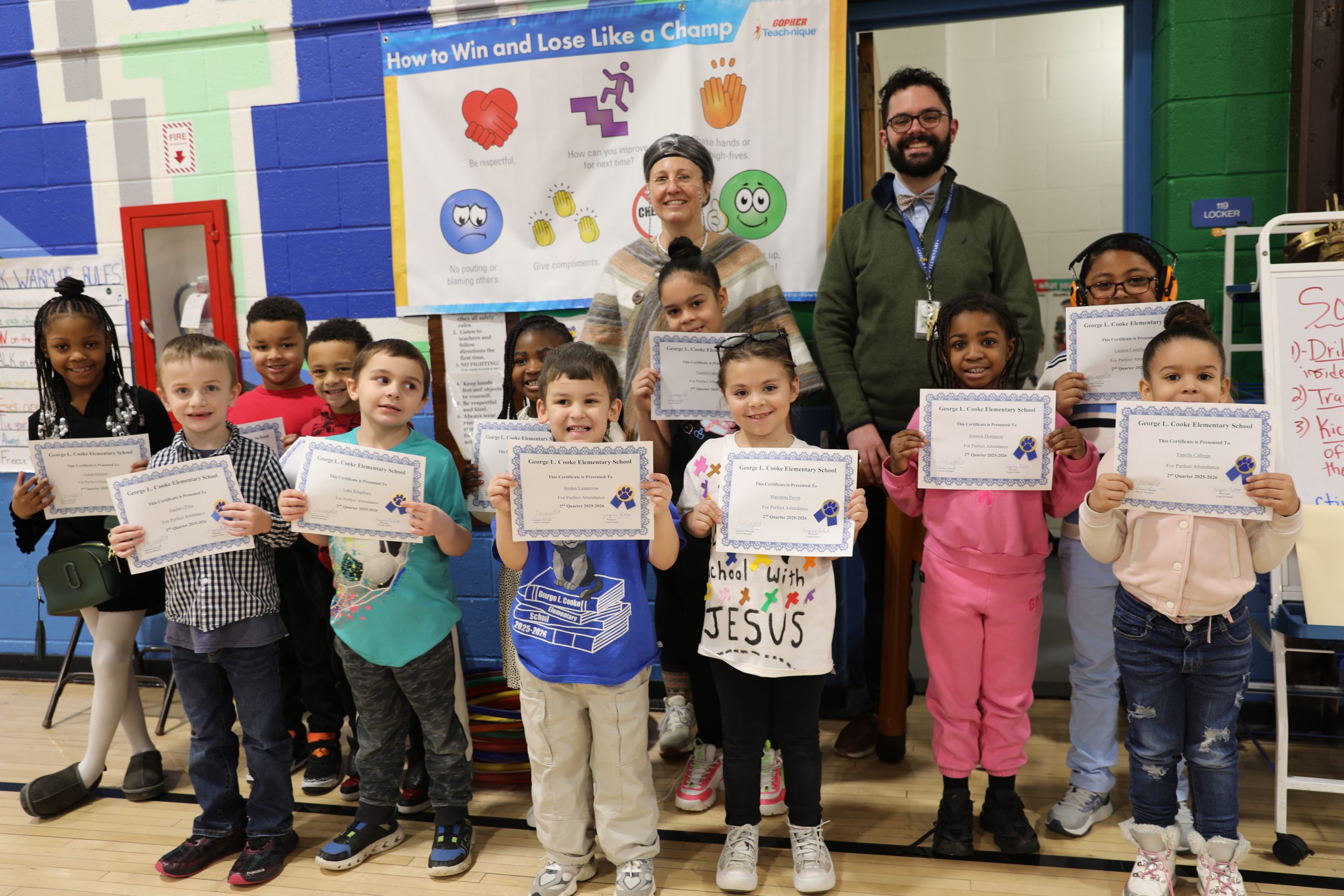 a group of students are posing in the gym holding up certificates they received for perfect attendance