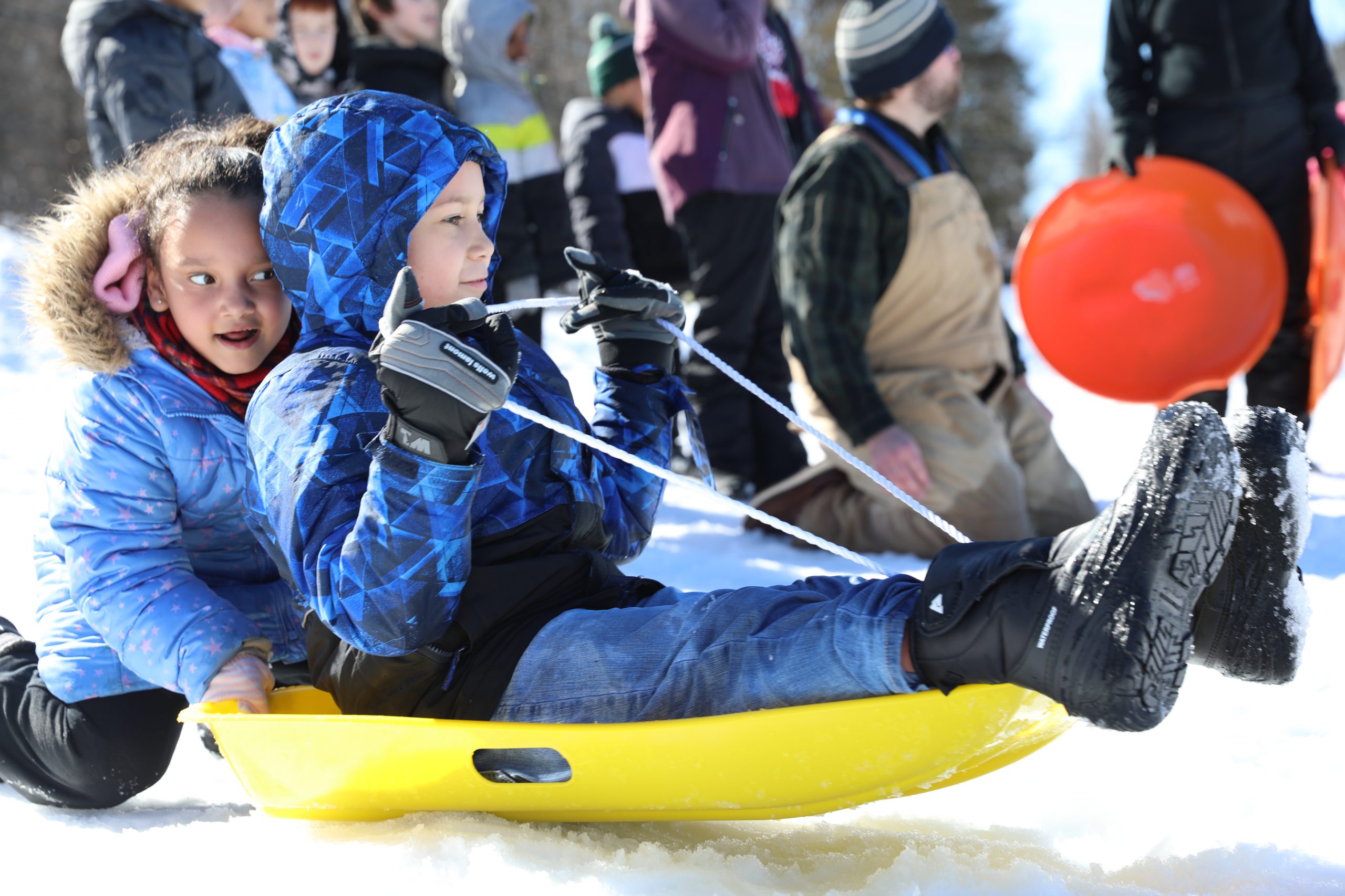 a student pushes another on a sled 