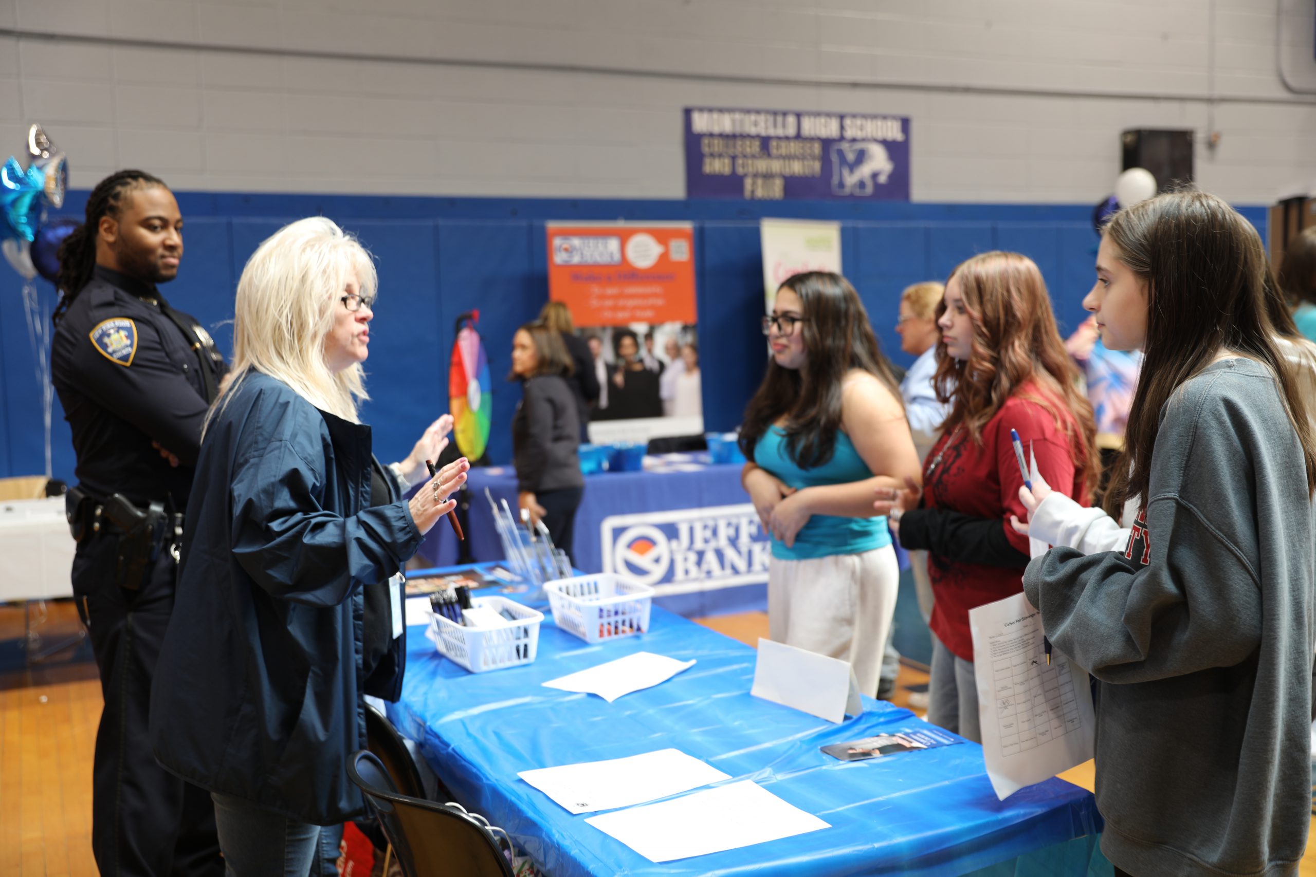 students are at a booth at the career fair speaking with a vendor
