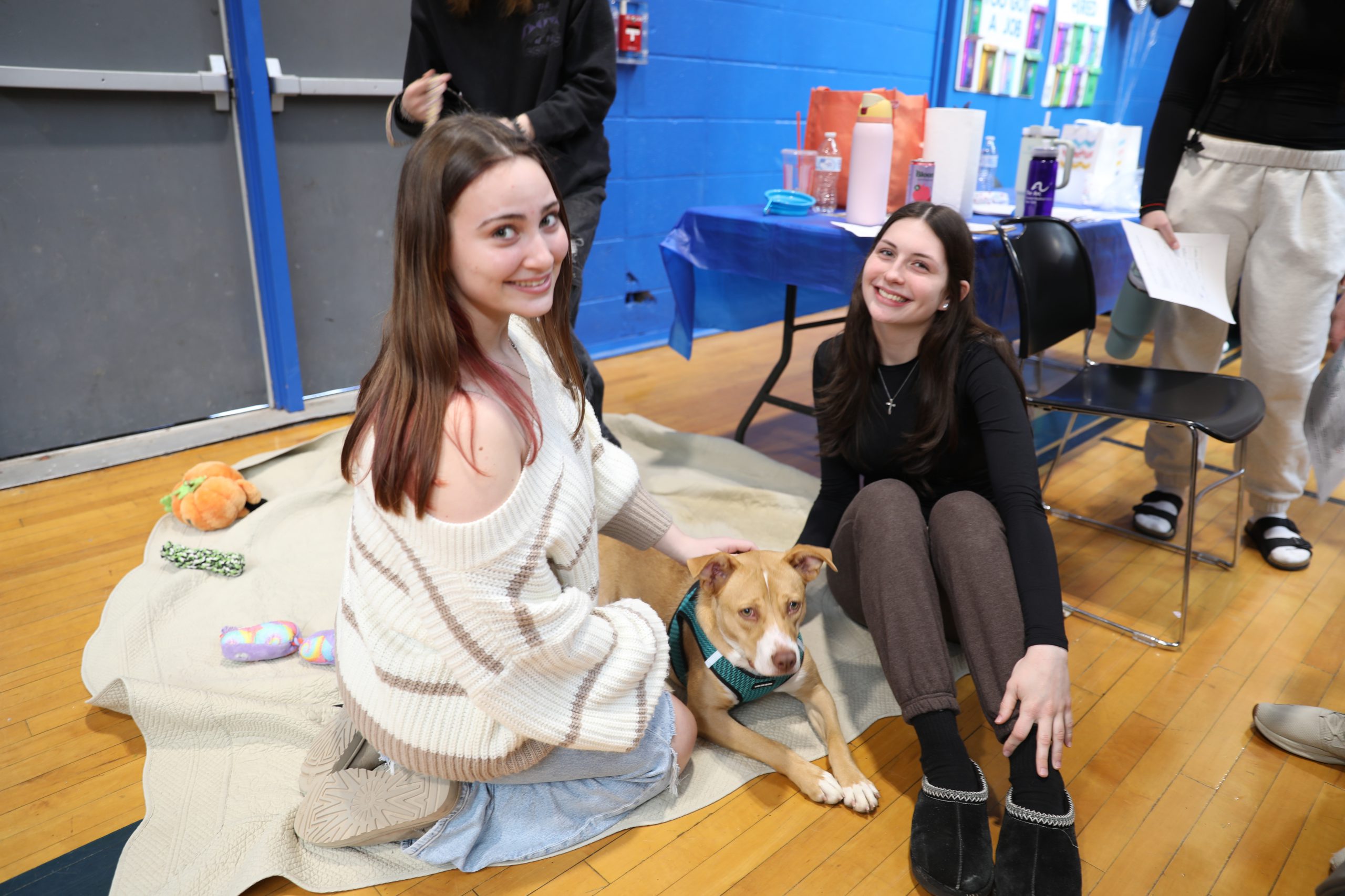 two students pet a dog visiting the career fair from the SPCA and smile for the camera