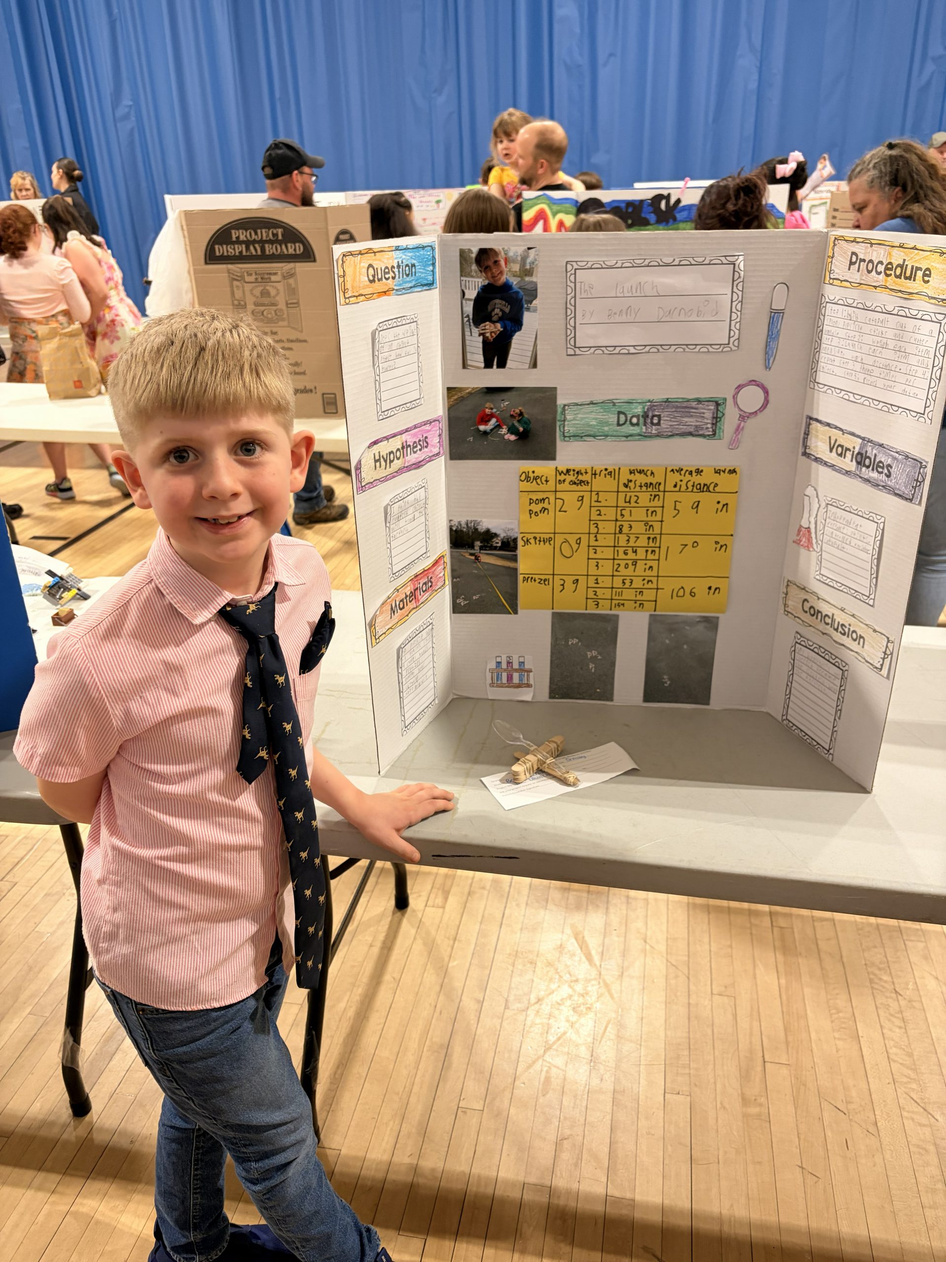 a student stands next to a diorama that explains his project