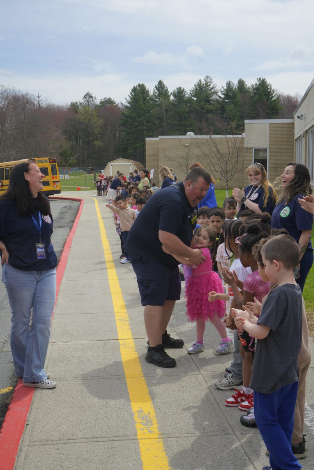 Firefighter Wayne hugs a girl who is standing with her classmates to cheer him on