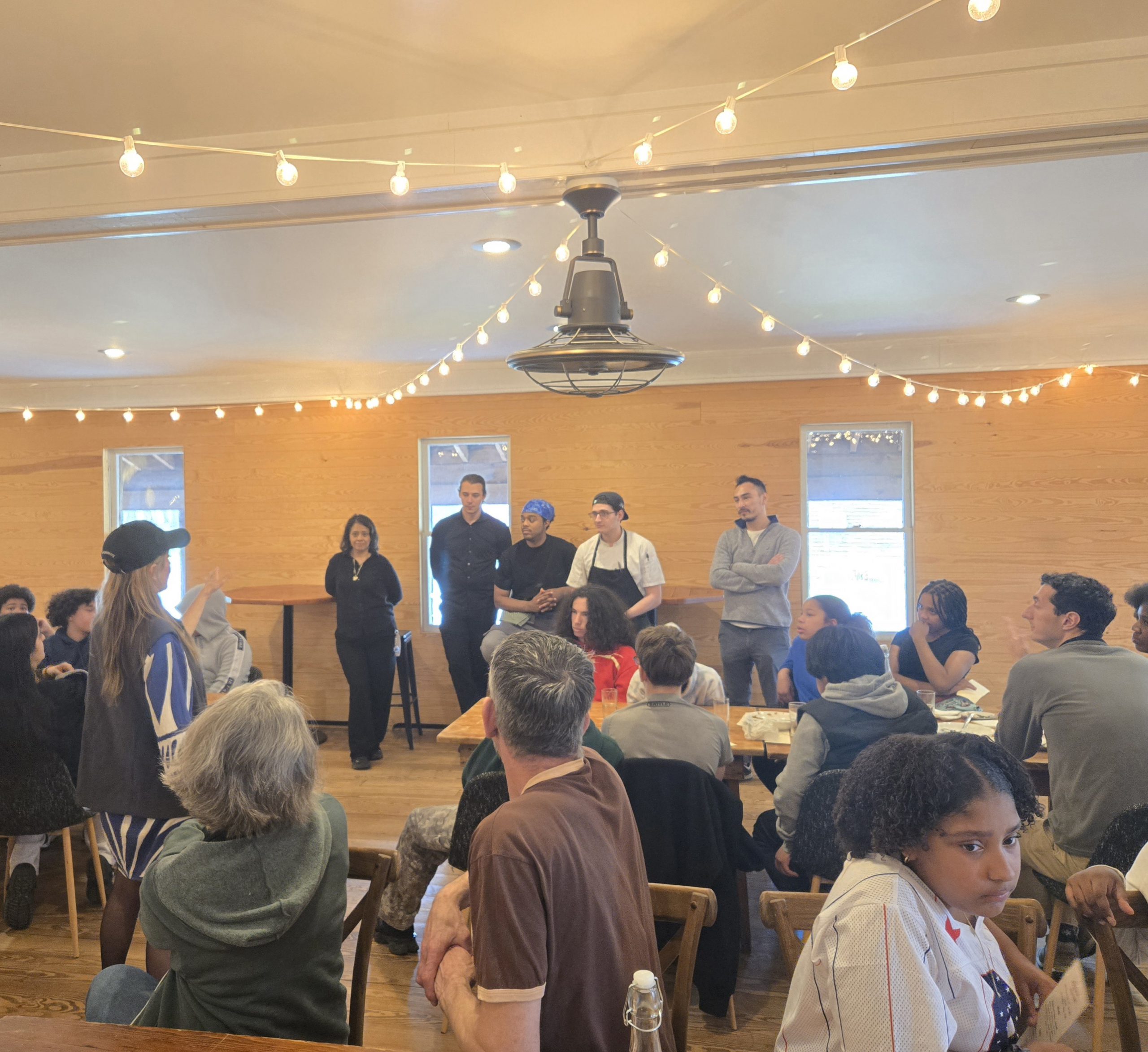a group of chefs are standing at the front of the room addressing a large group of students