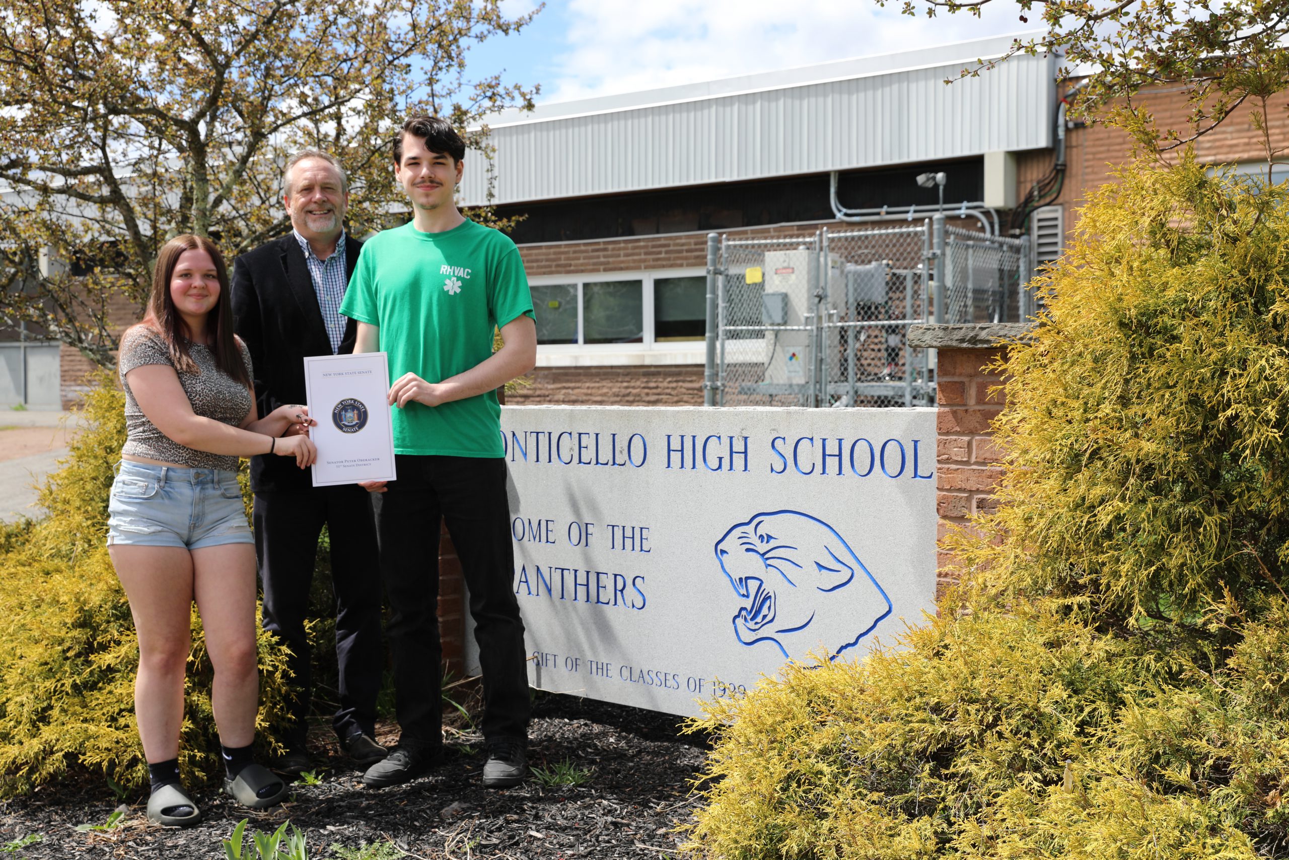 Emma and Gavin pose with Senator Peter Oberacker outside Monticello High School