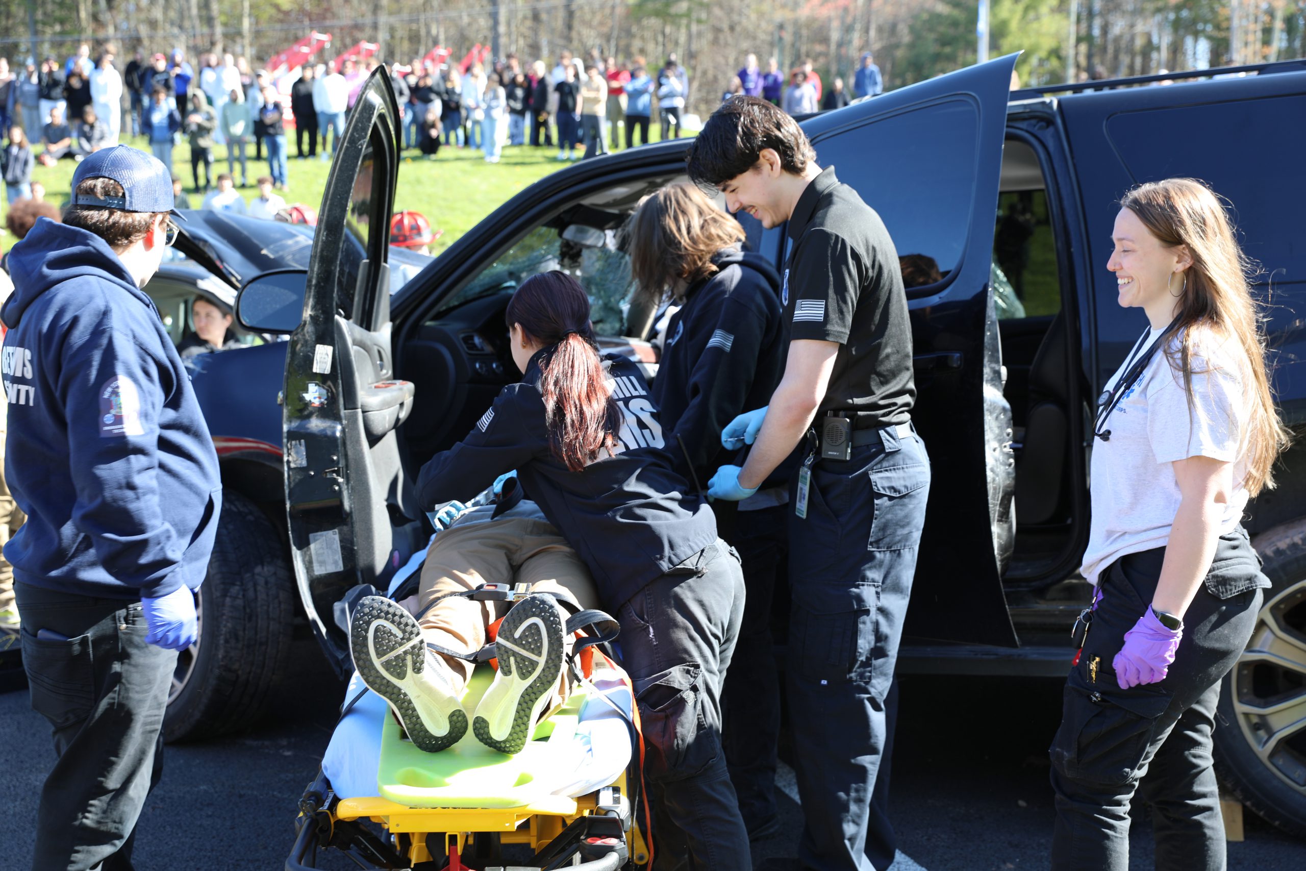 Gavin works with other EMTs to load an actor on to a stretcher as part of the mock crash drill 