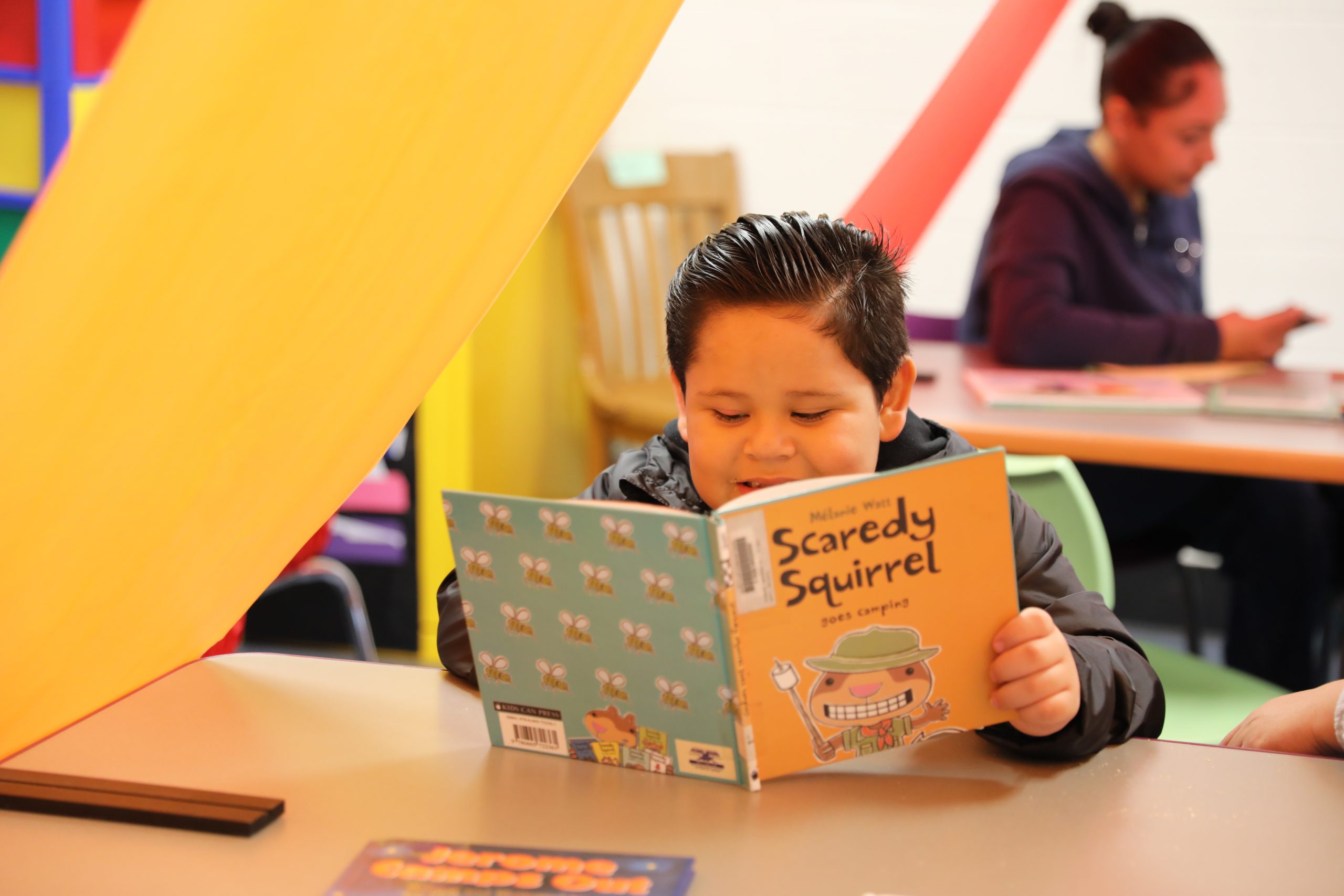 a student reads a book under a tent set up in the library. 