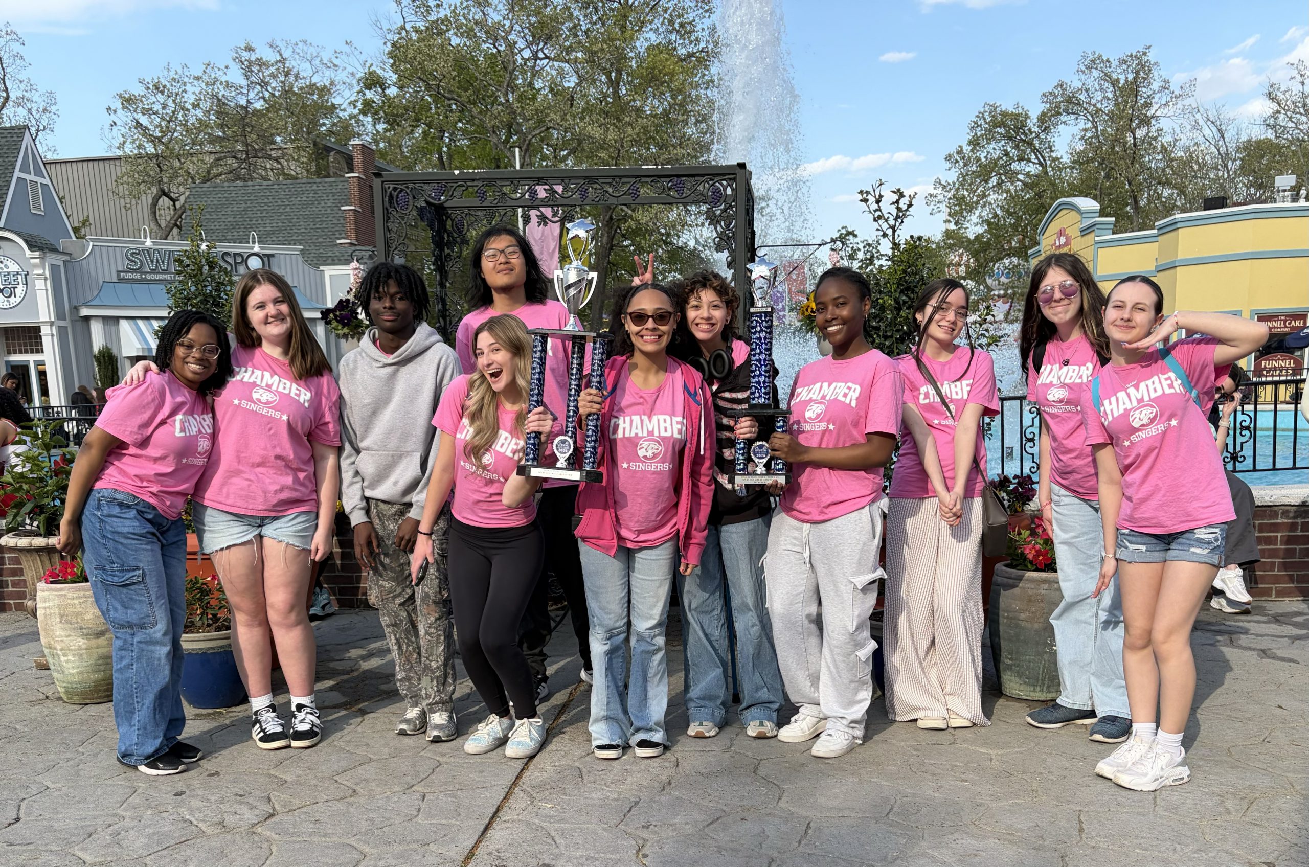 a group of students in pink shirts pose at music in the parks 