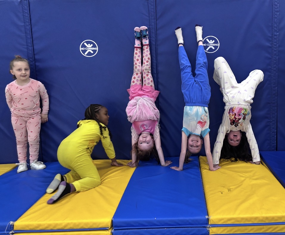 students are doing handstands in the gym against a brightly colored wall 