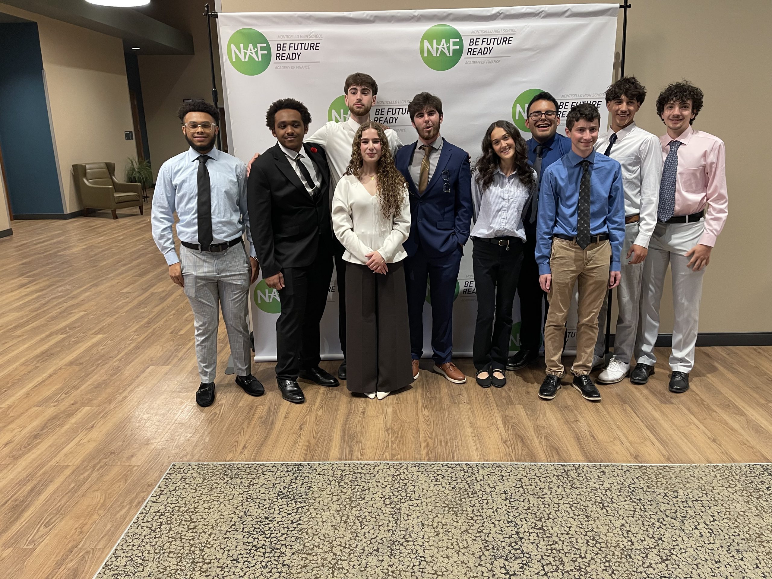 a group of students pose in interview attire behind an AOF backdrop